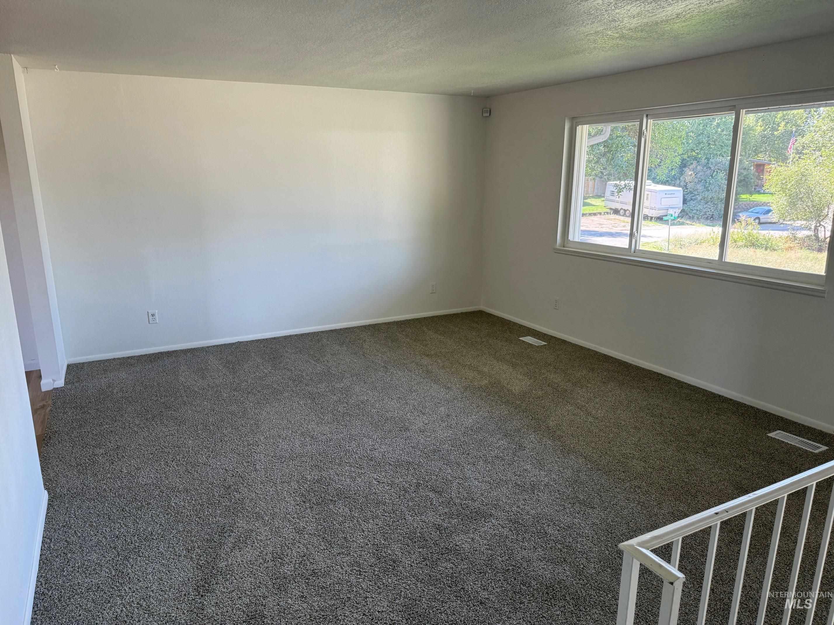 Spare room with dark carpet and a textured ceiling
