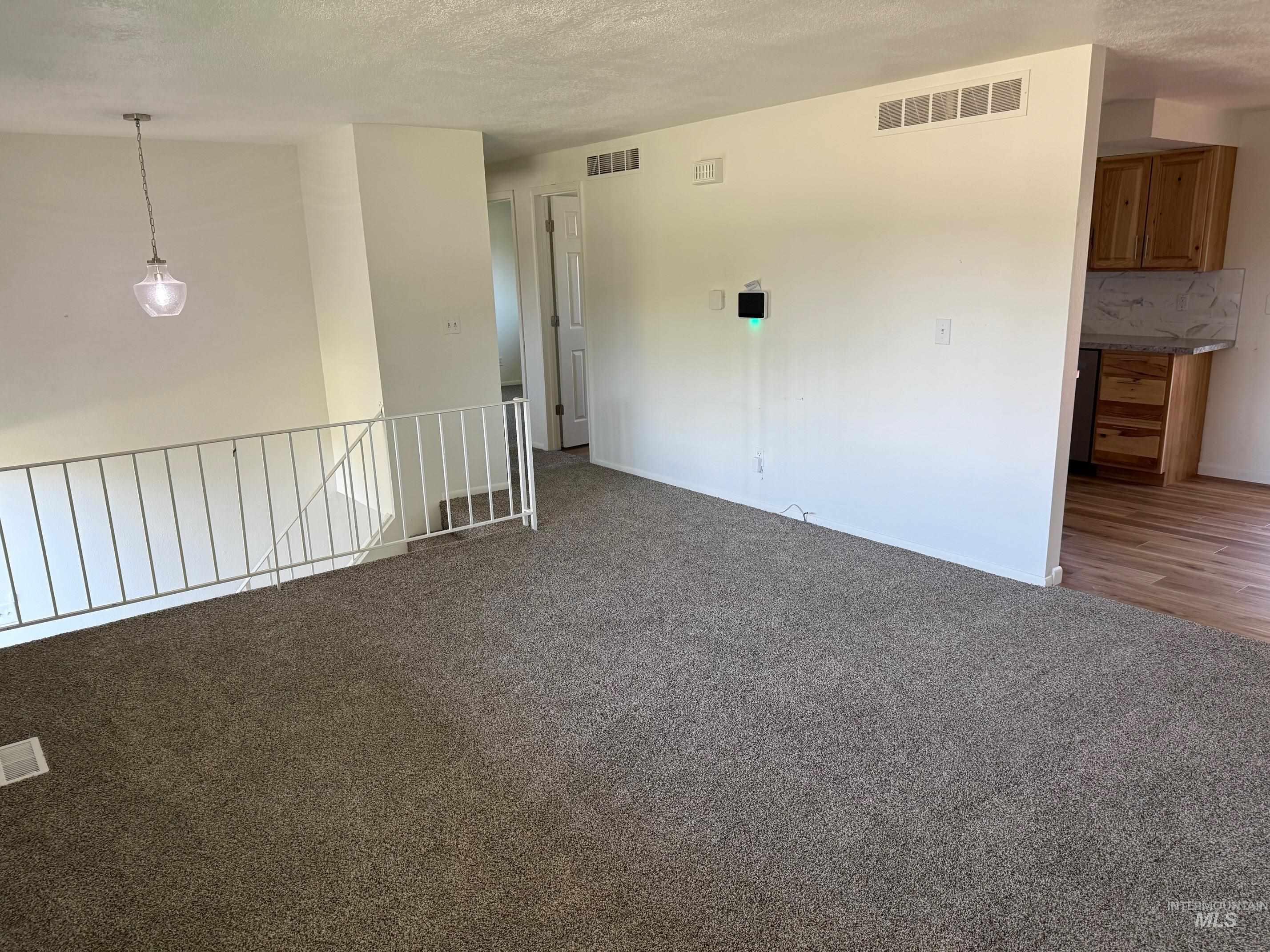 Unfurnished room featuring light colored carpet and a textured ceiling