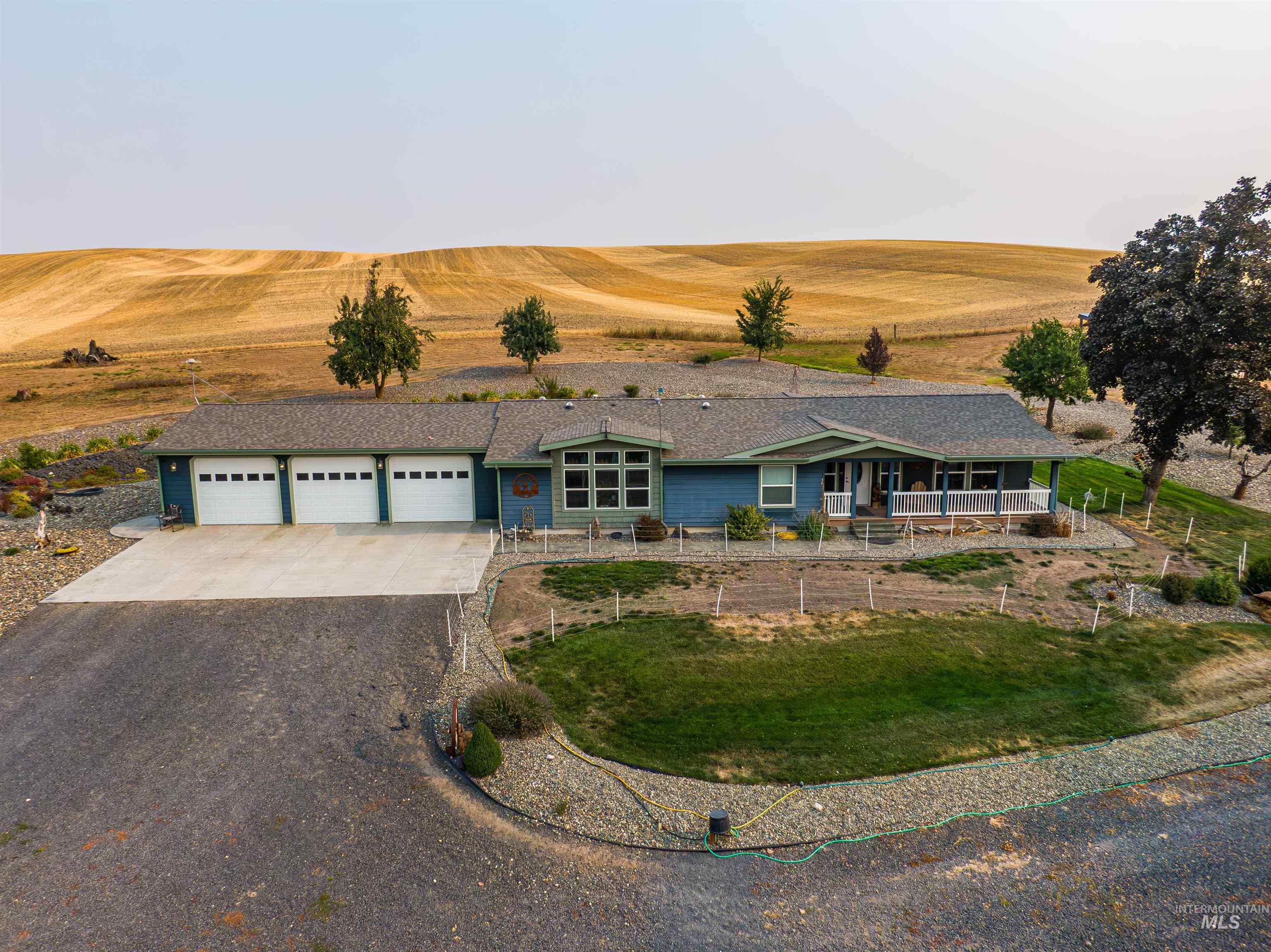 View of front facade featuring driveway, a garage, a patio, and a shingled roof