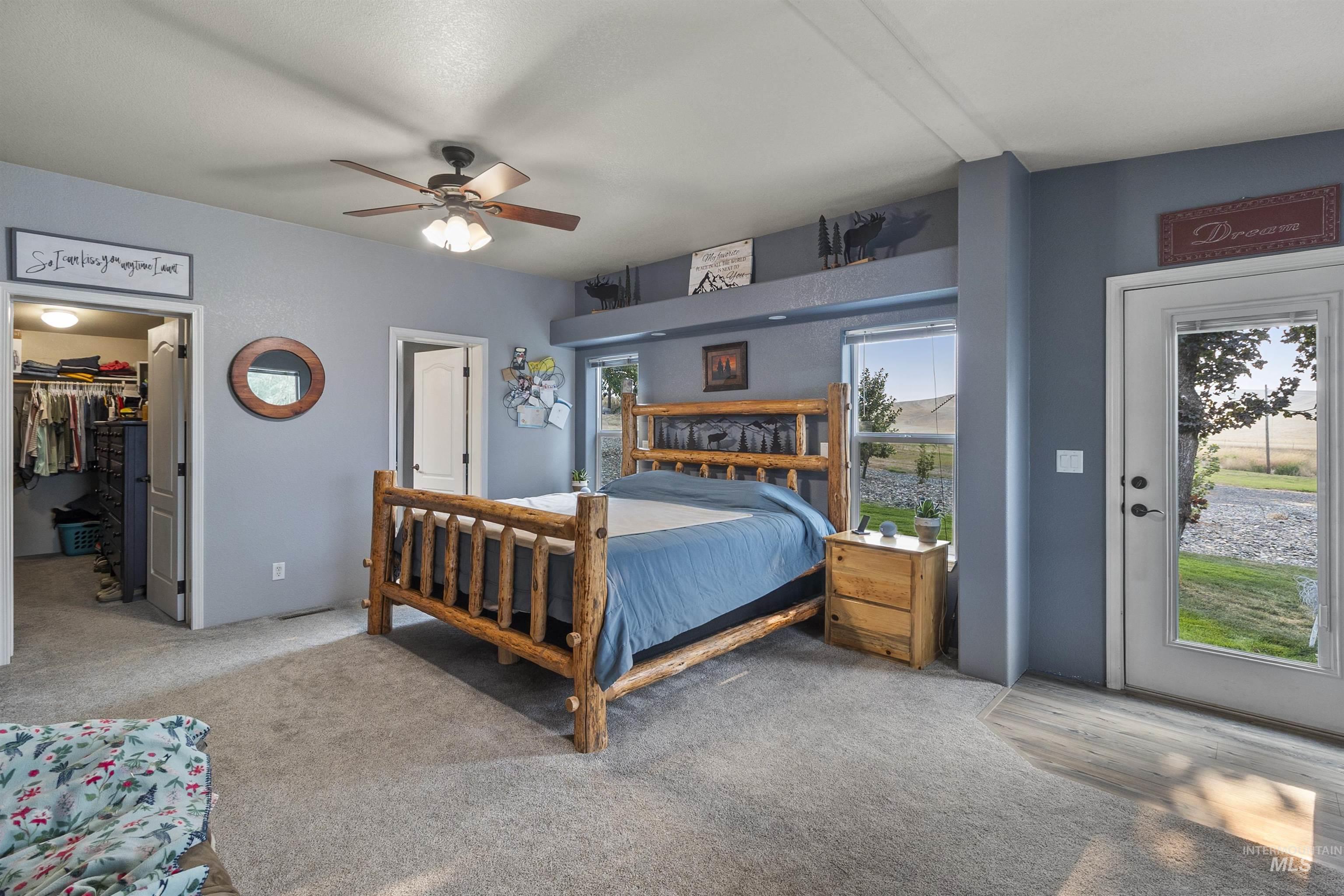 Carpeted bedroom with a spacious closet, ceiling fan, and access to exterior
