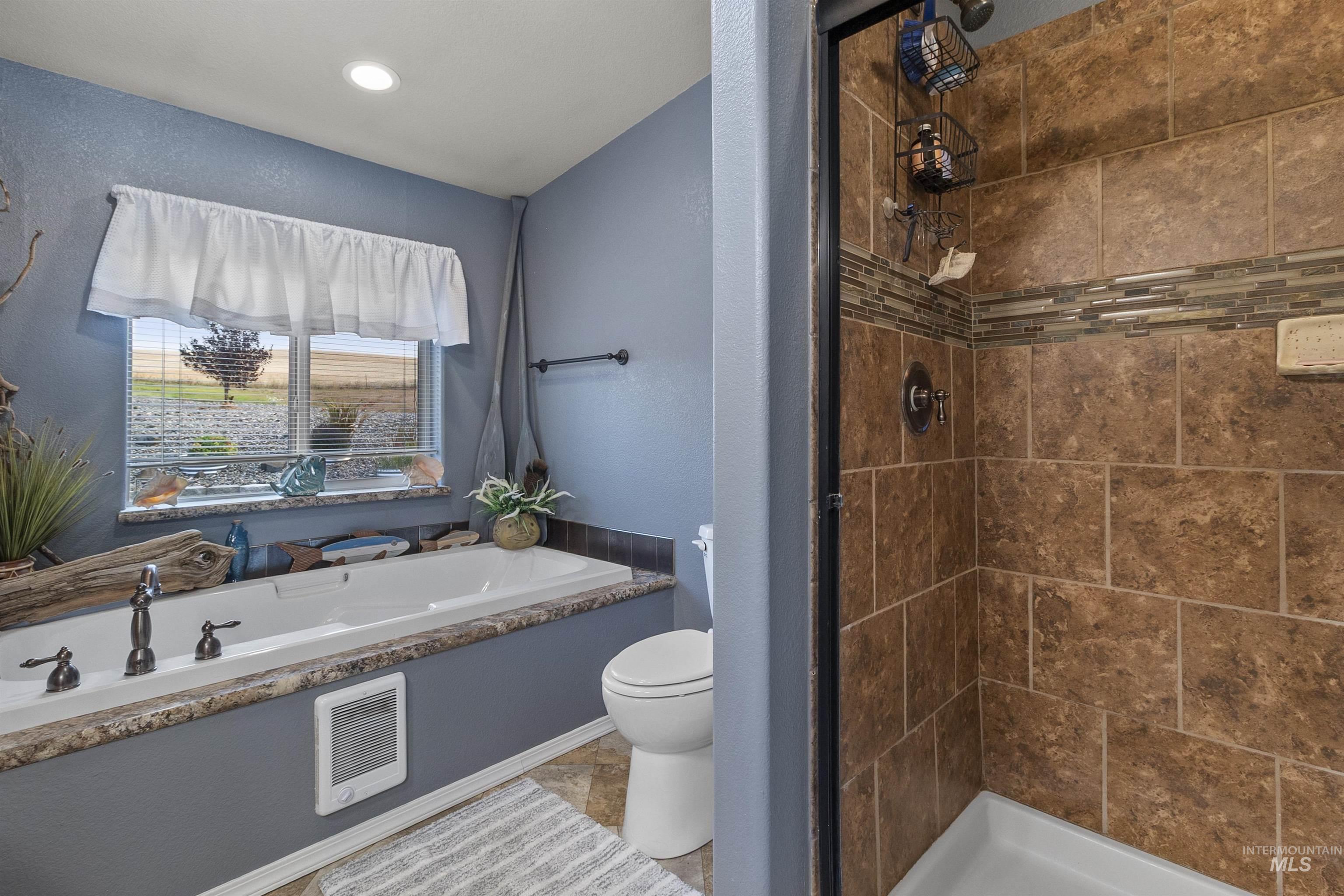 Bathroom with a textured wall, a shower stall, a garden tub, and heating unit