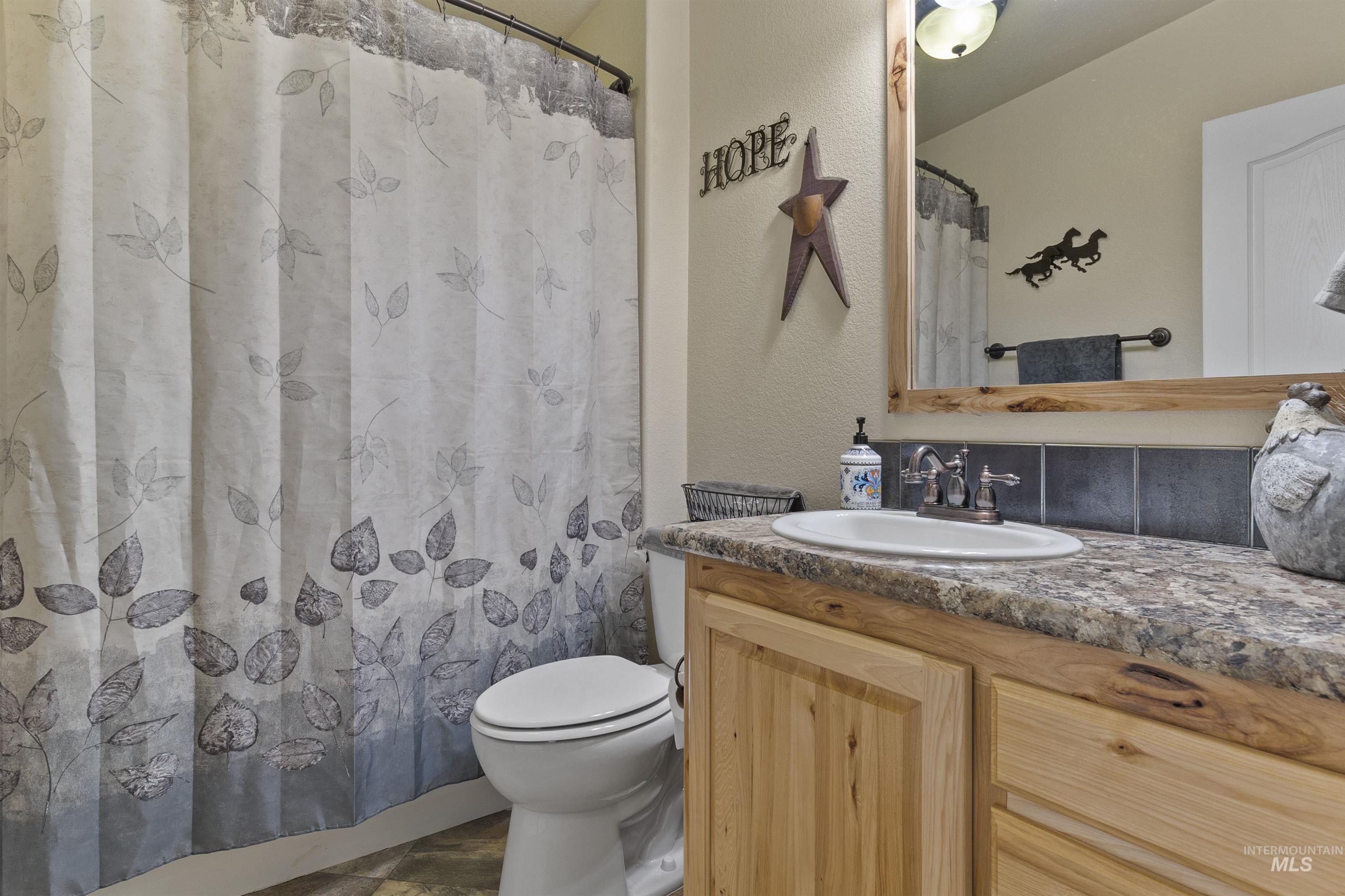 Full bathroom with a textured wall, vanity, and curtained shower