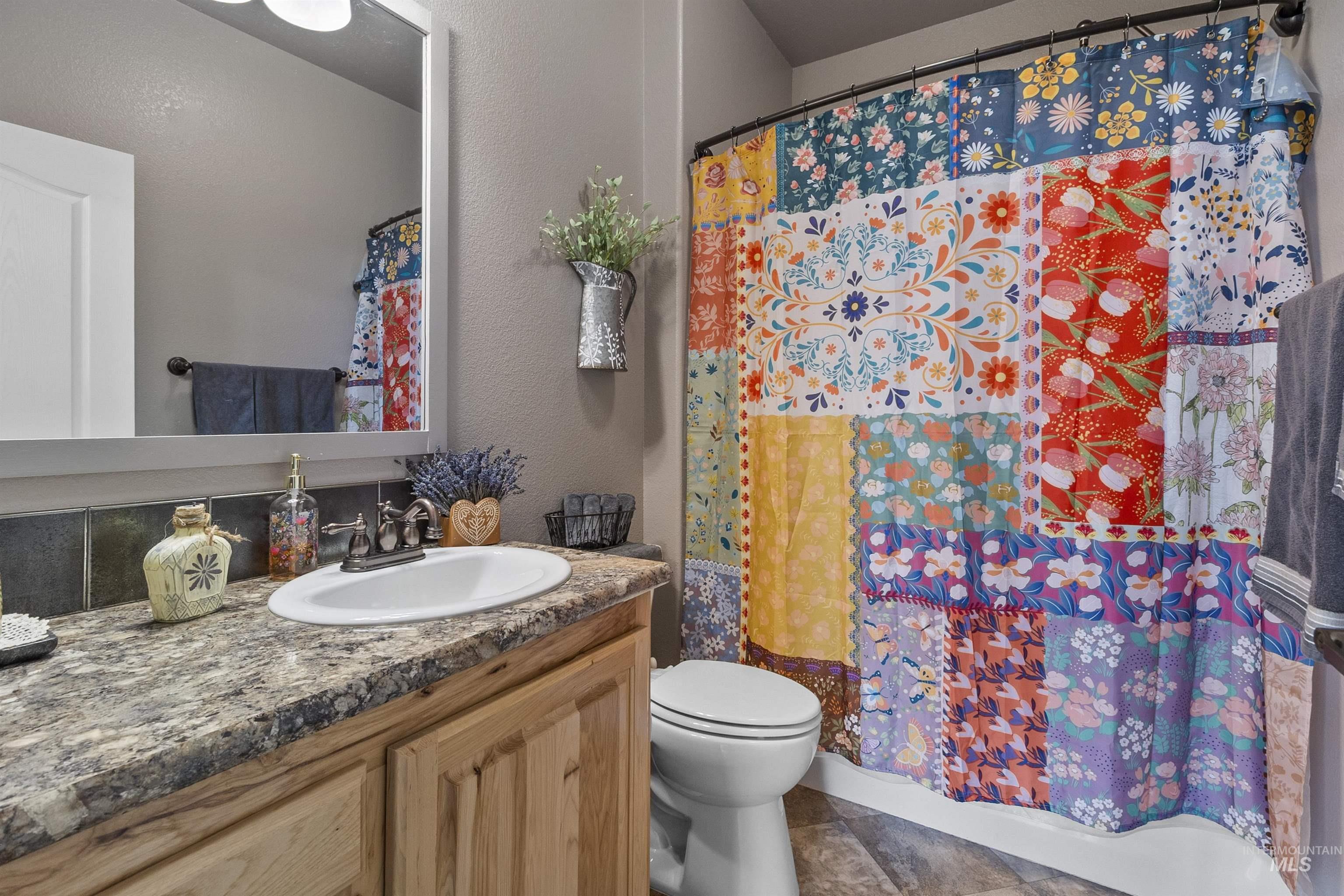 Full bath featuring vanity, a textured wall, and shower / bathtub combination with curtain