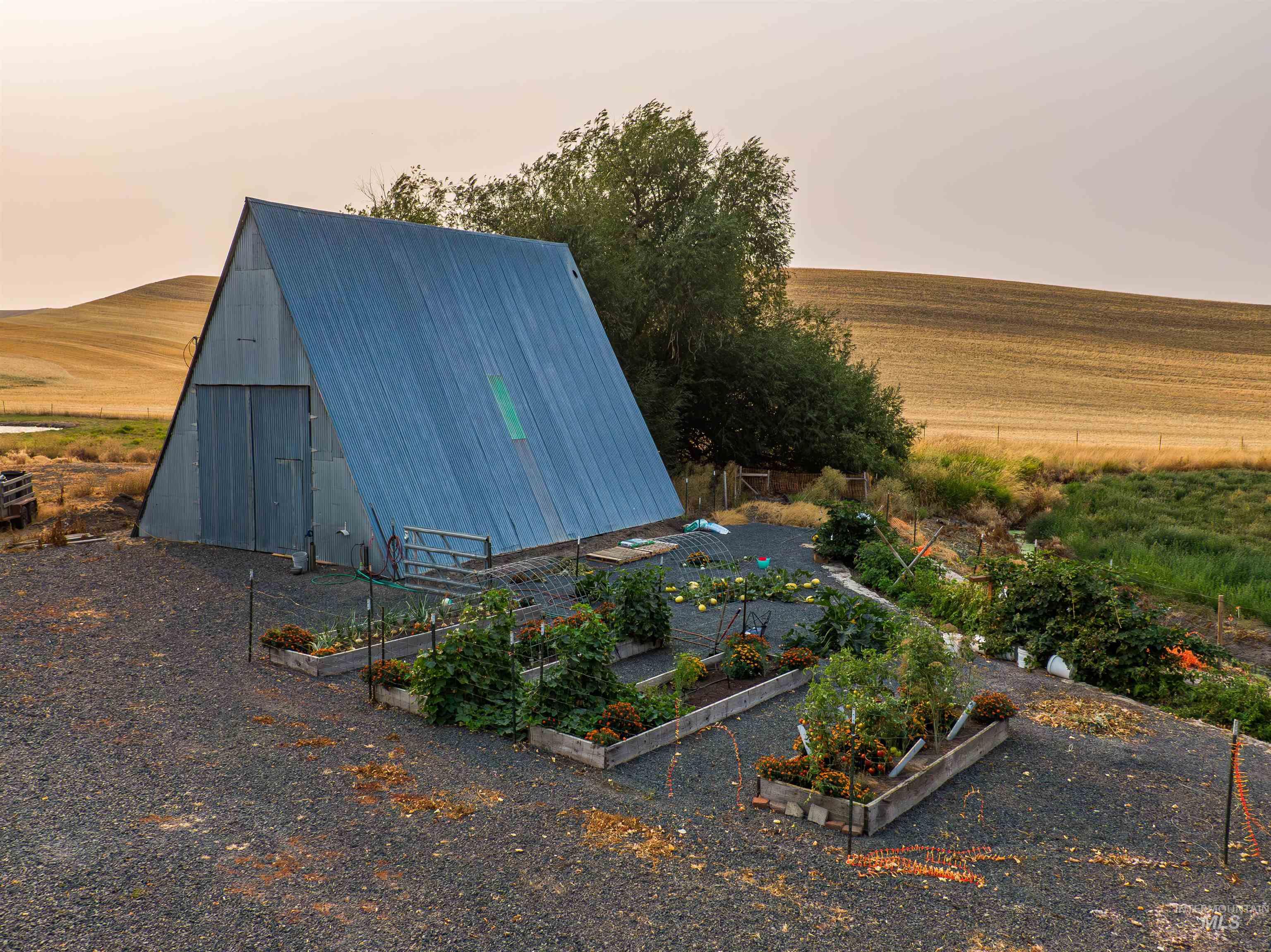 View of pole building with a garden and a rural view