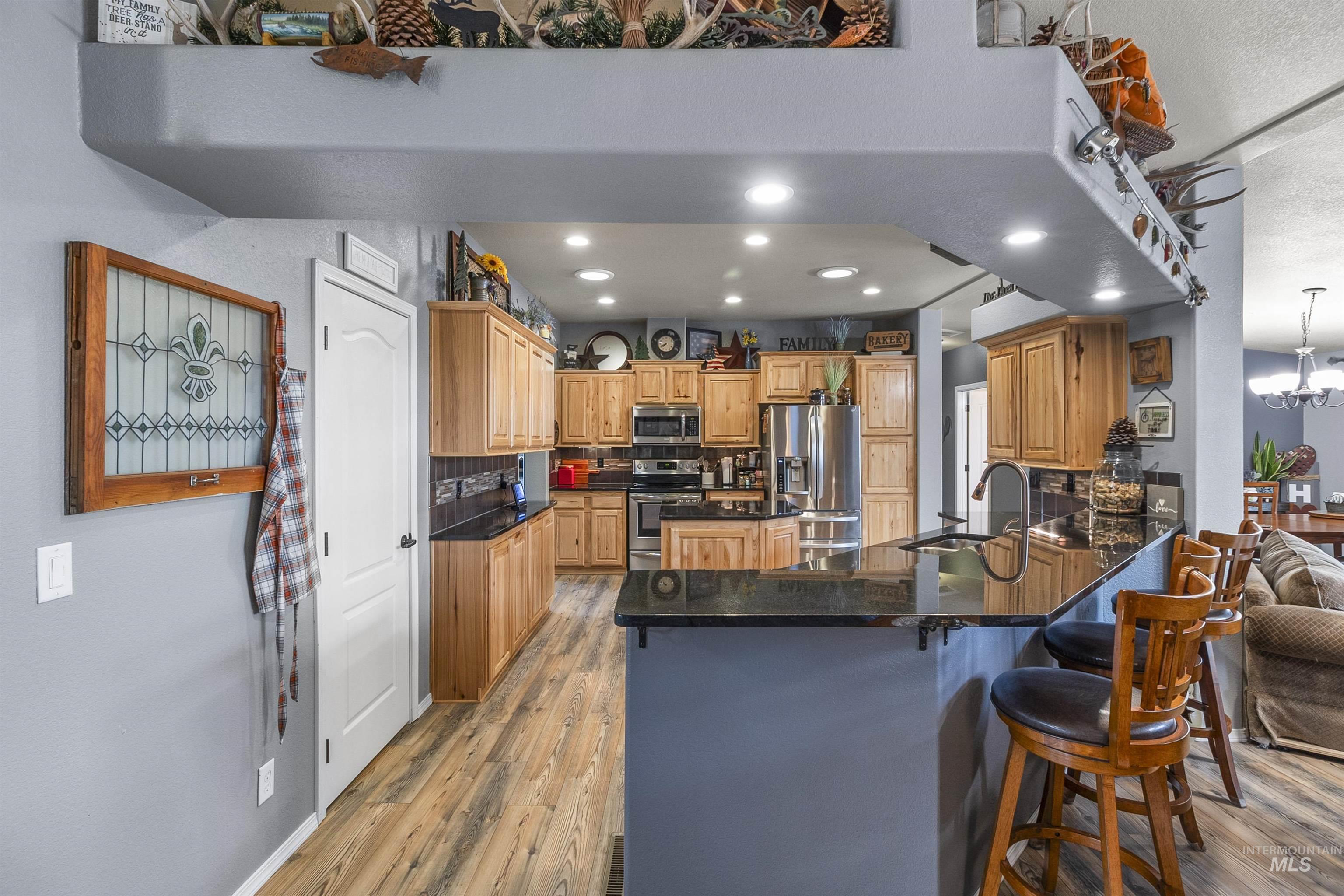 Kitchen featuring tasteful backsplash, appliances with stainless steel finishes, light wood-style flooring, a breakfast bar area, and recessed lighting