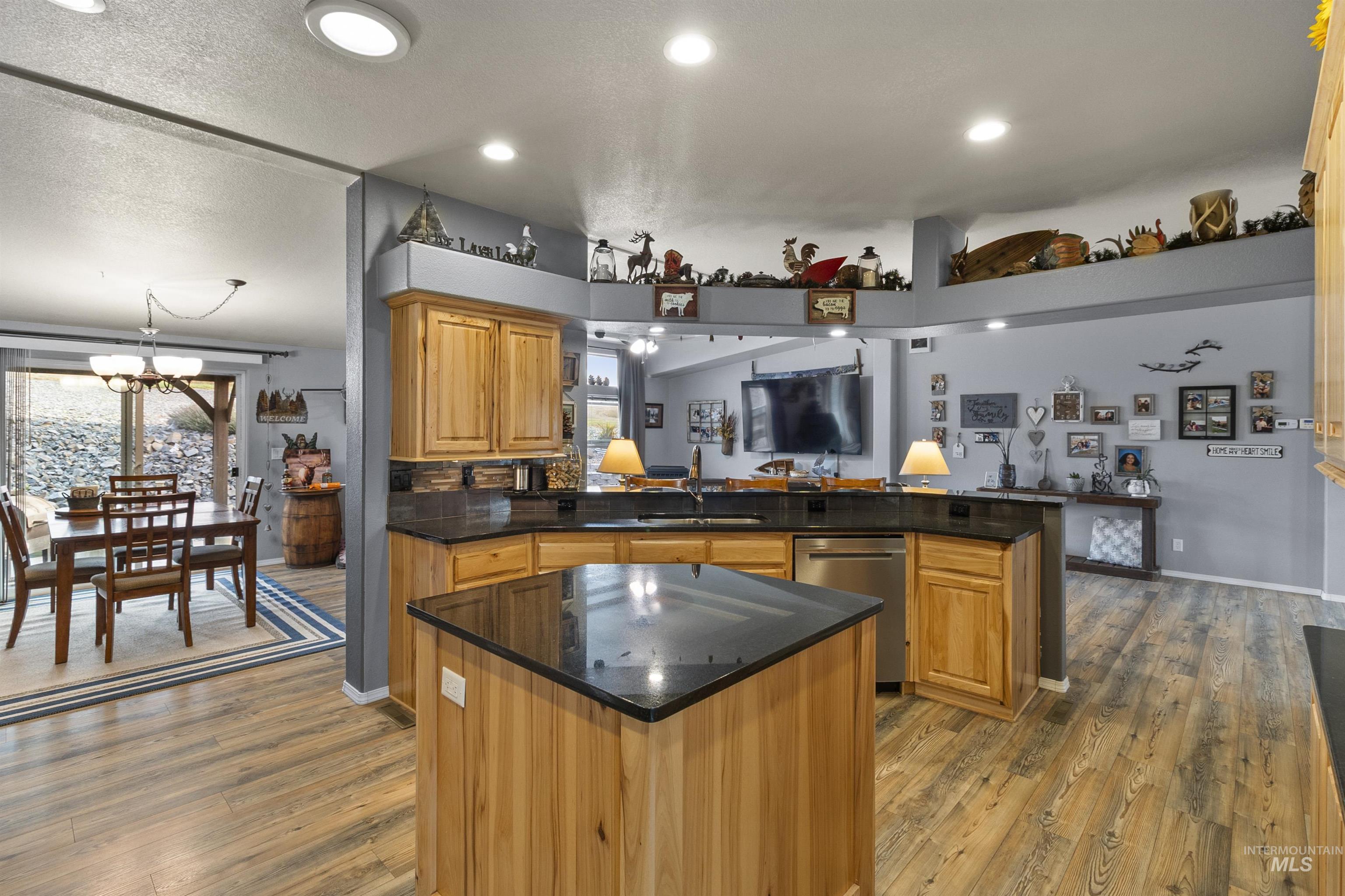 Kitchen featuring a center island, light wood-style floors, brown cabinets, dishwasher, and a chandelier