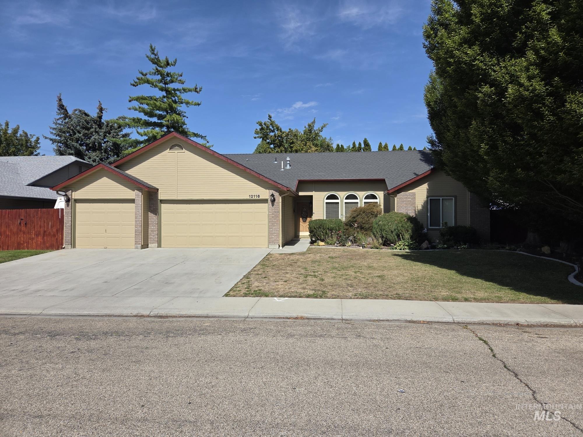 Ranch-style home with a 3 car garage, concrete driveway, a front yard, and brick siding