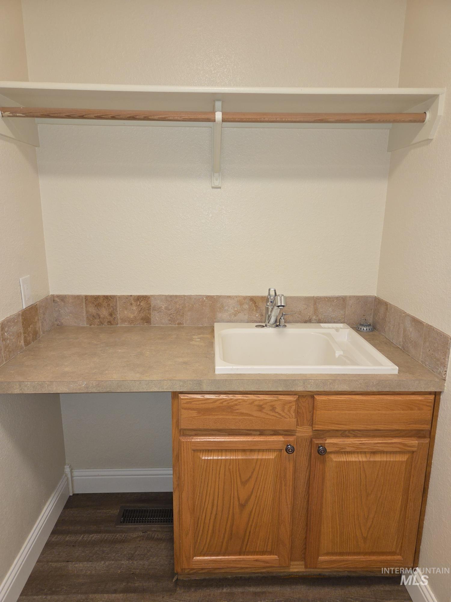 Laundry room featuring a textured wall and dark wood finished floors