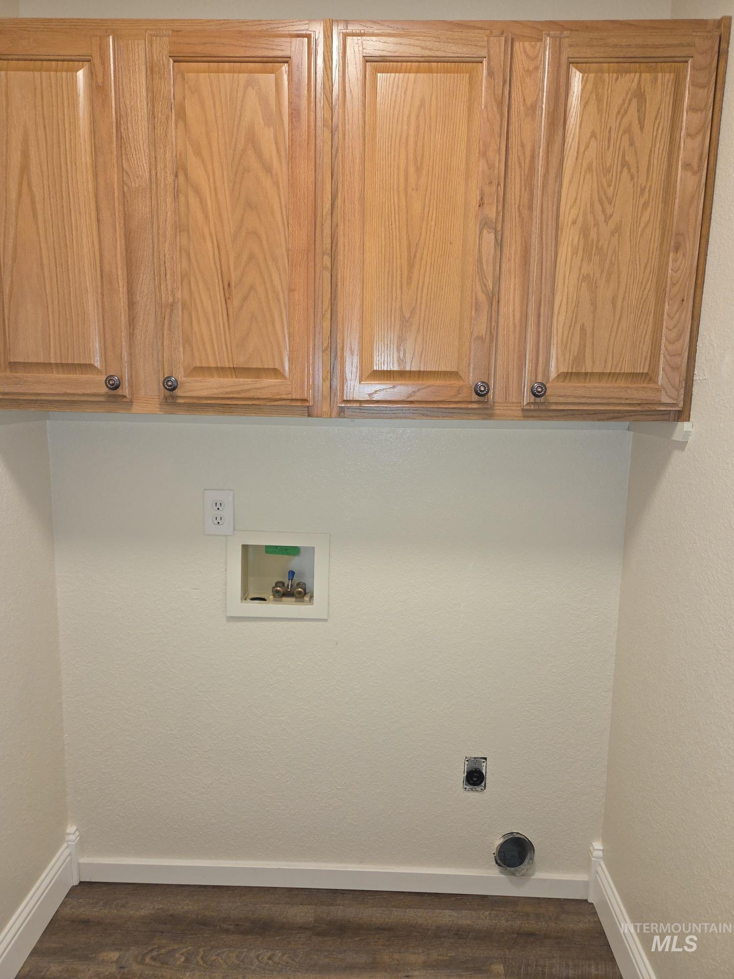 Washroom with cabinet space, dark wood finished floors, washer hookup, and hookup for an electric dryer