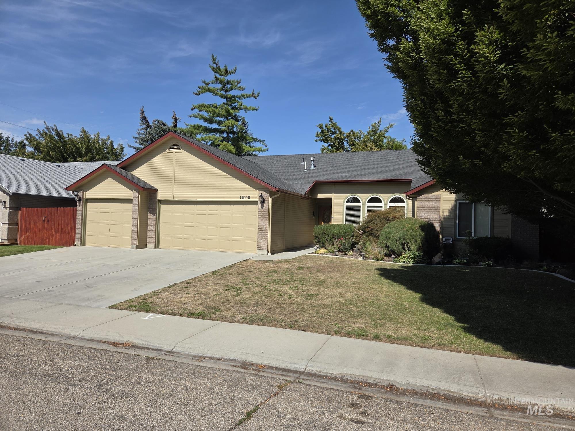 Ranch-style house with driveway, an attached garage, brick siding, and a front lawn