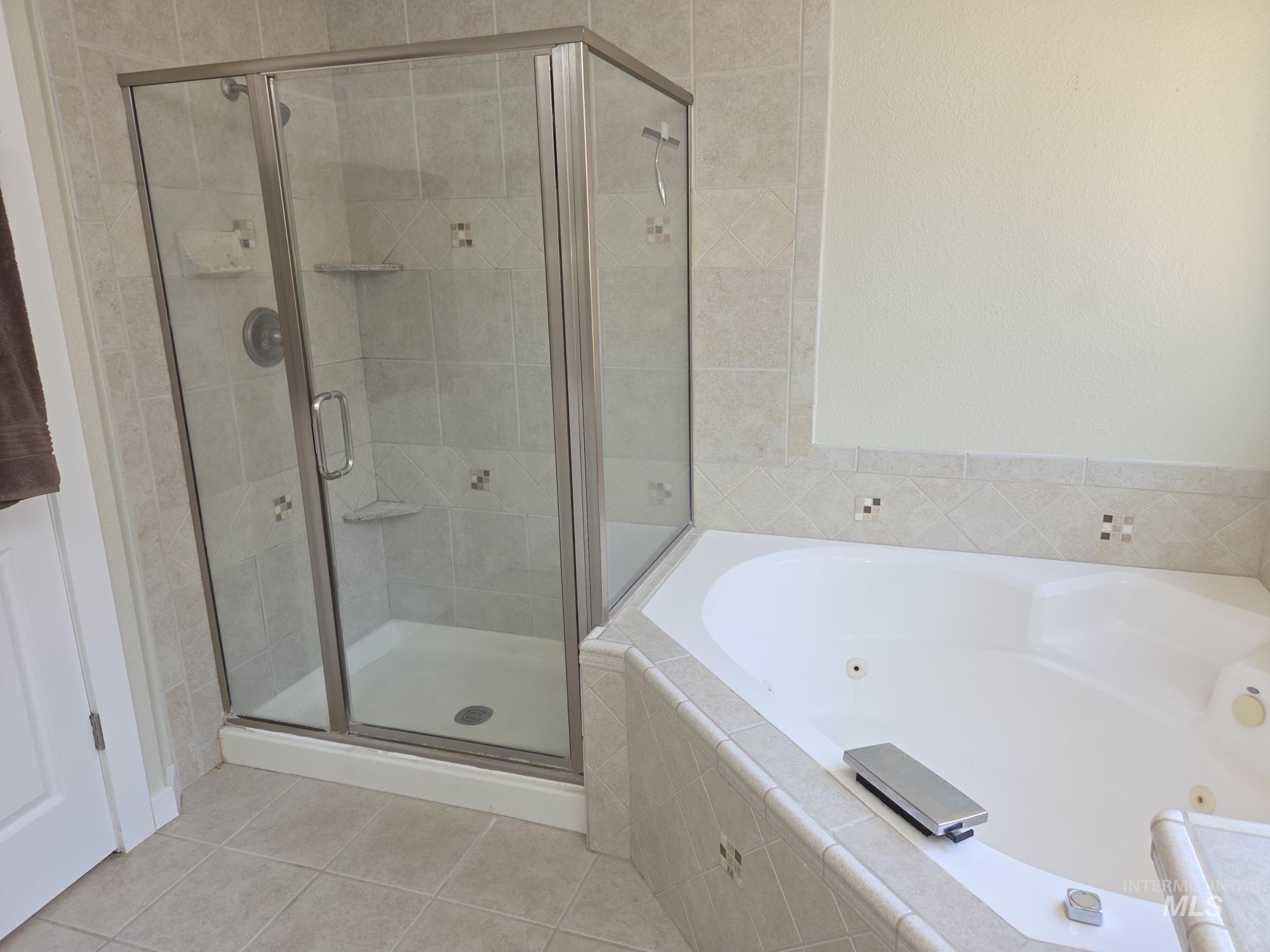 Bathroom with a shower stall, a whirlpool tub, and light tile patterned flooring
