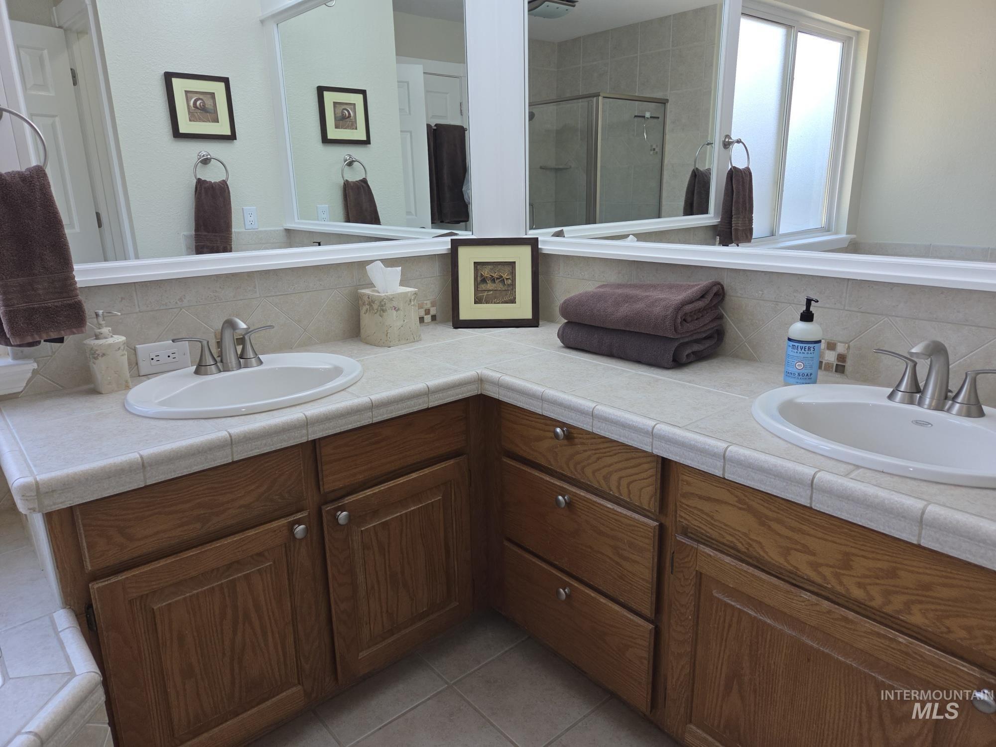 Bathroom with tasteful backsplash, double vanity, and a shower stall