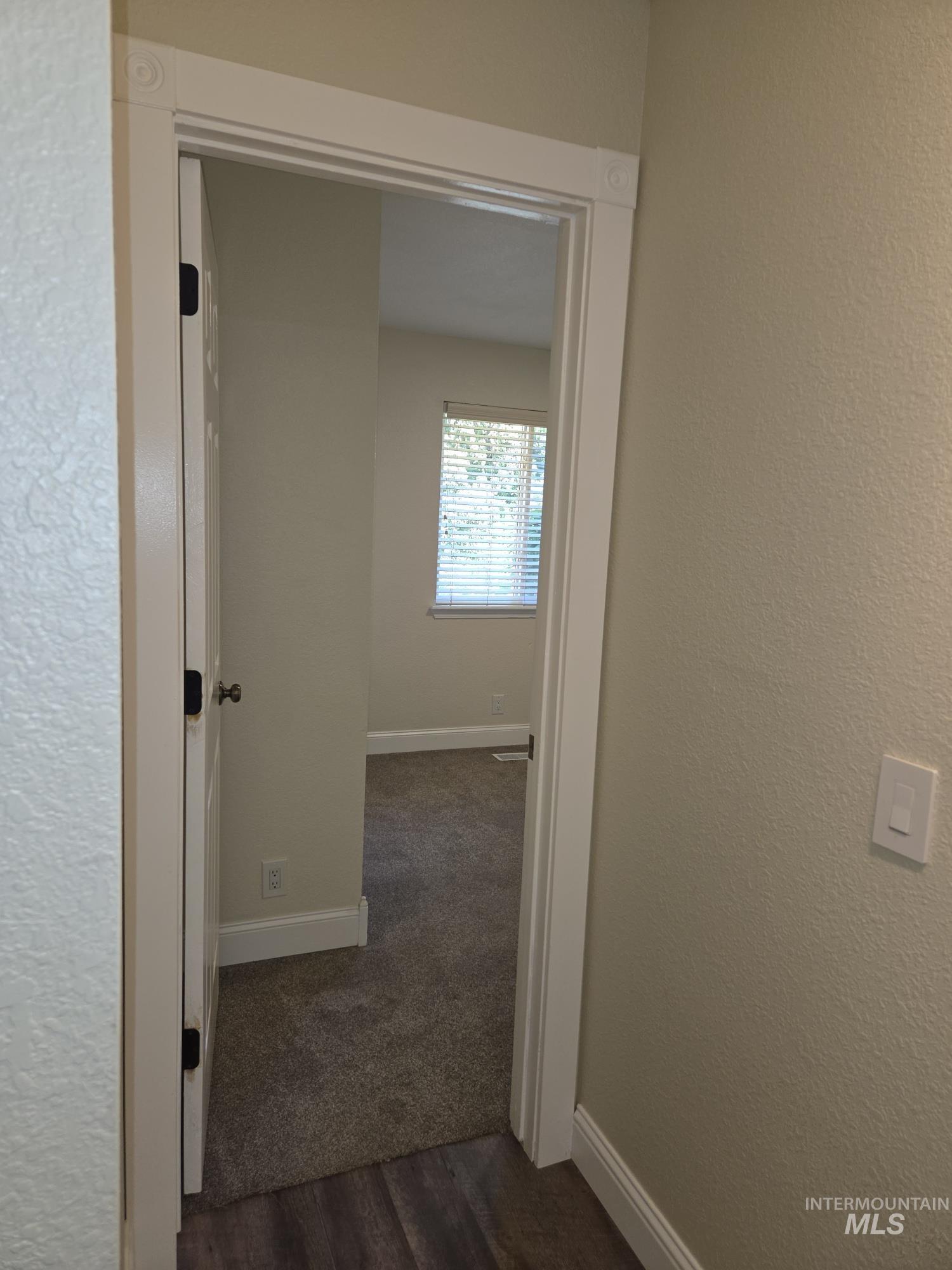 Hallway with dark wood finished floors and a textured wall