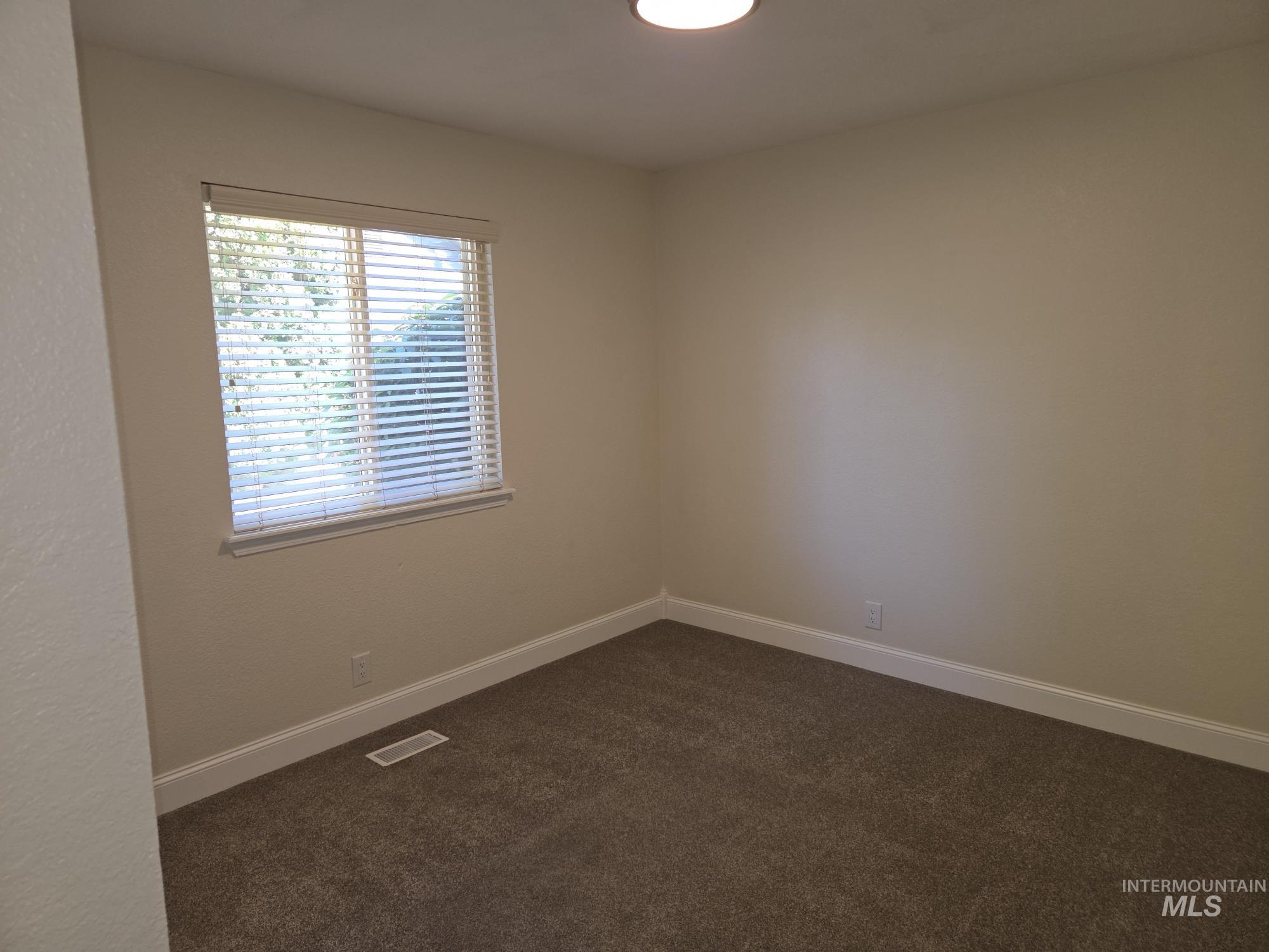 Empty room featuring dark carpet and baseboards