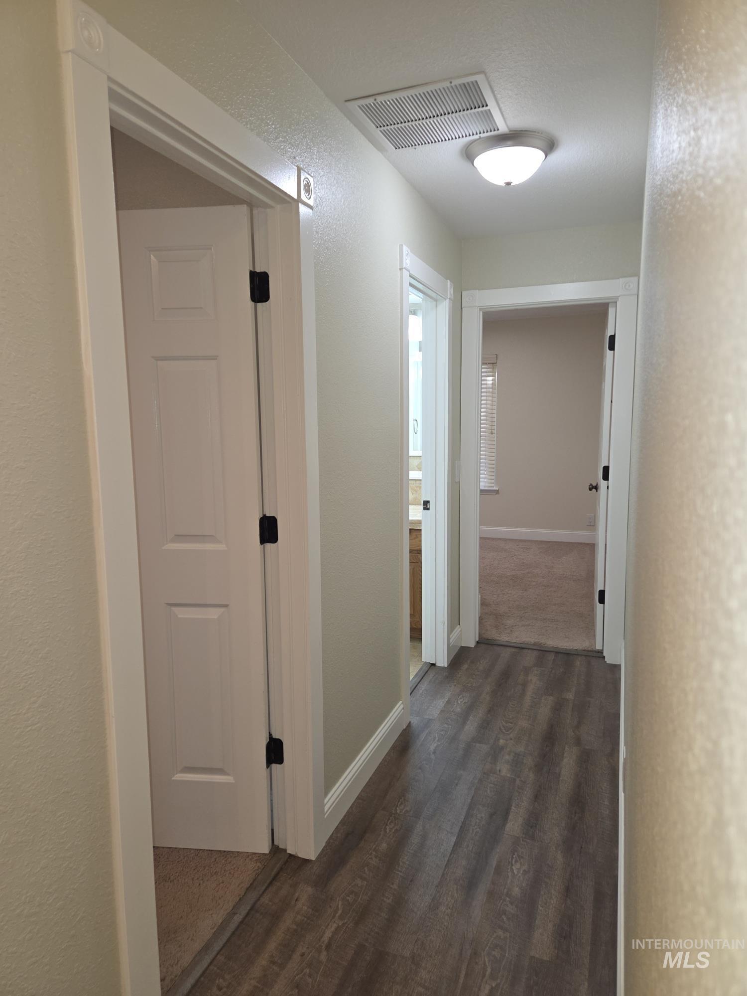 Hallway with a textured wall and dark wood-style floors