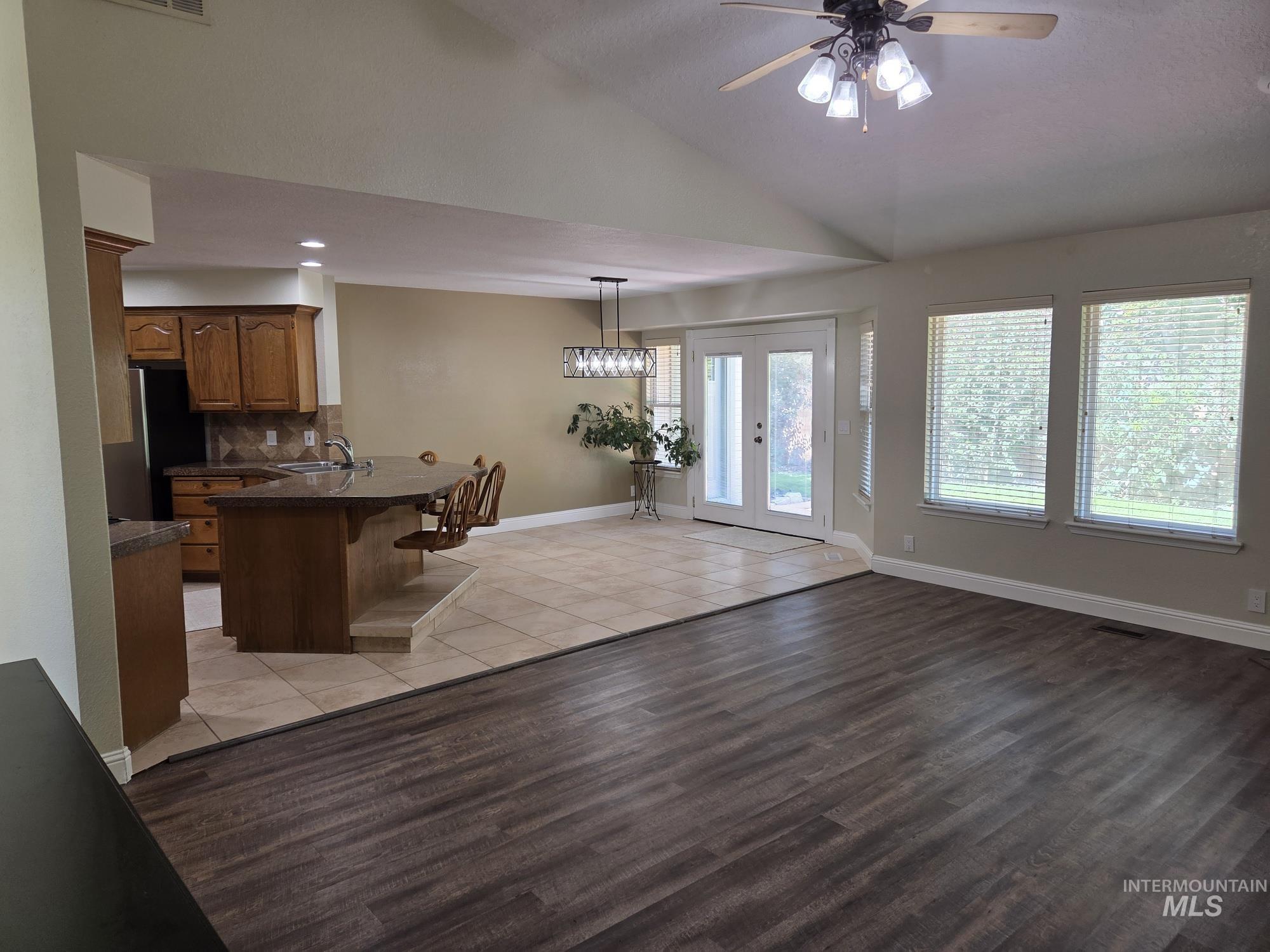 Kitchen featuring a kitchen breakfast bar, lofted ceiling, open floor plan, a peninsula, and freestanding refrigerator