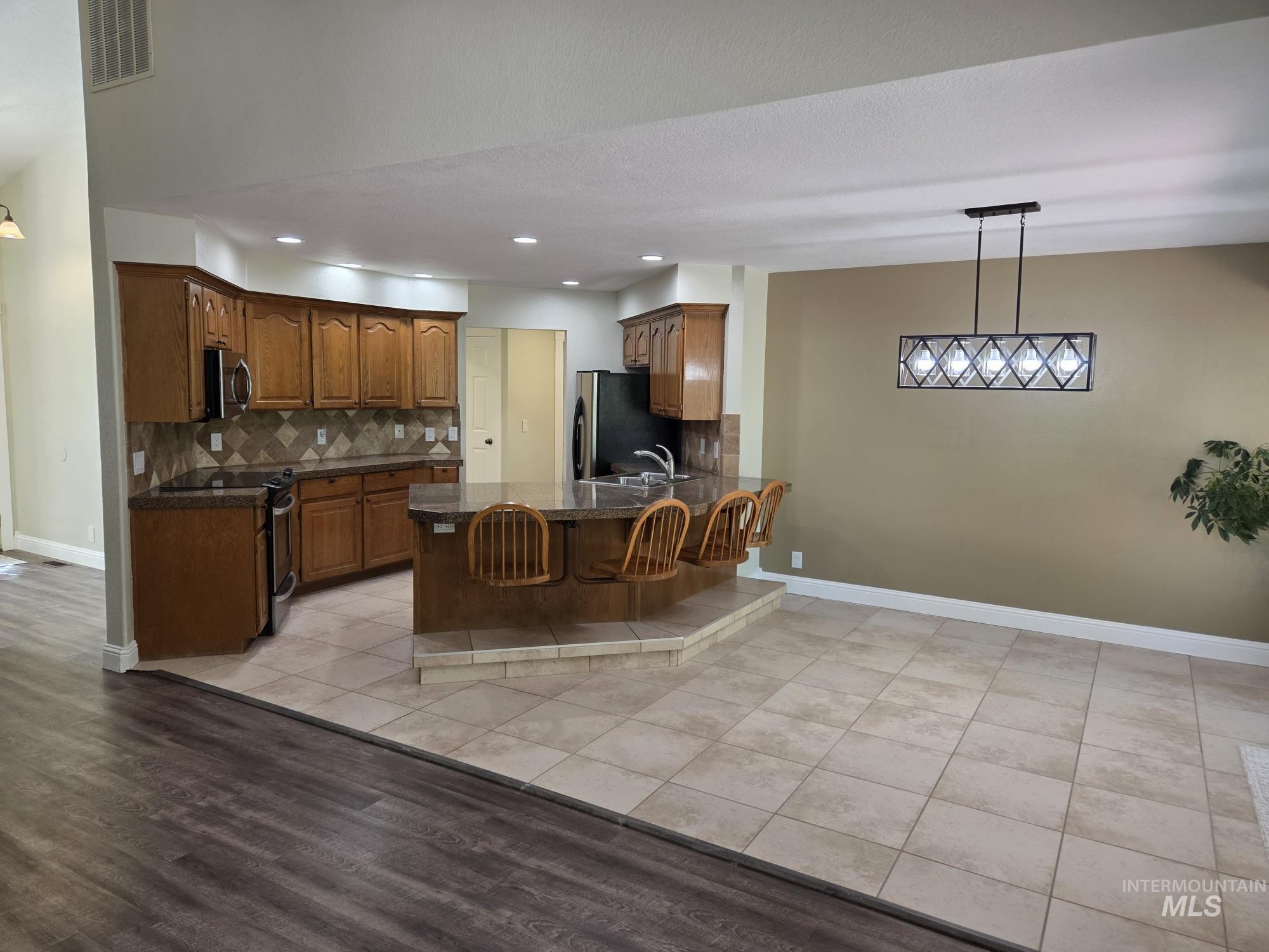 Kitchen with hanging light fixtures, tasteful backsplash, a breakfast bar, a peninsula, and recessed lighting