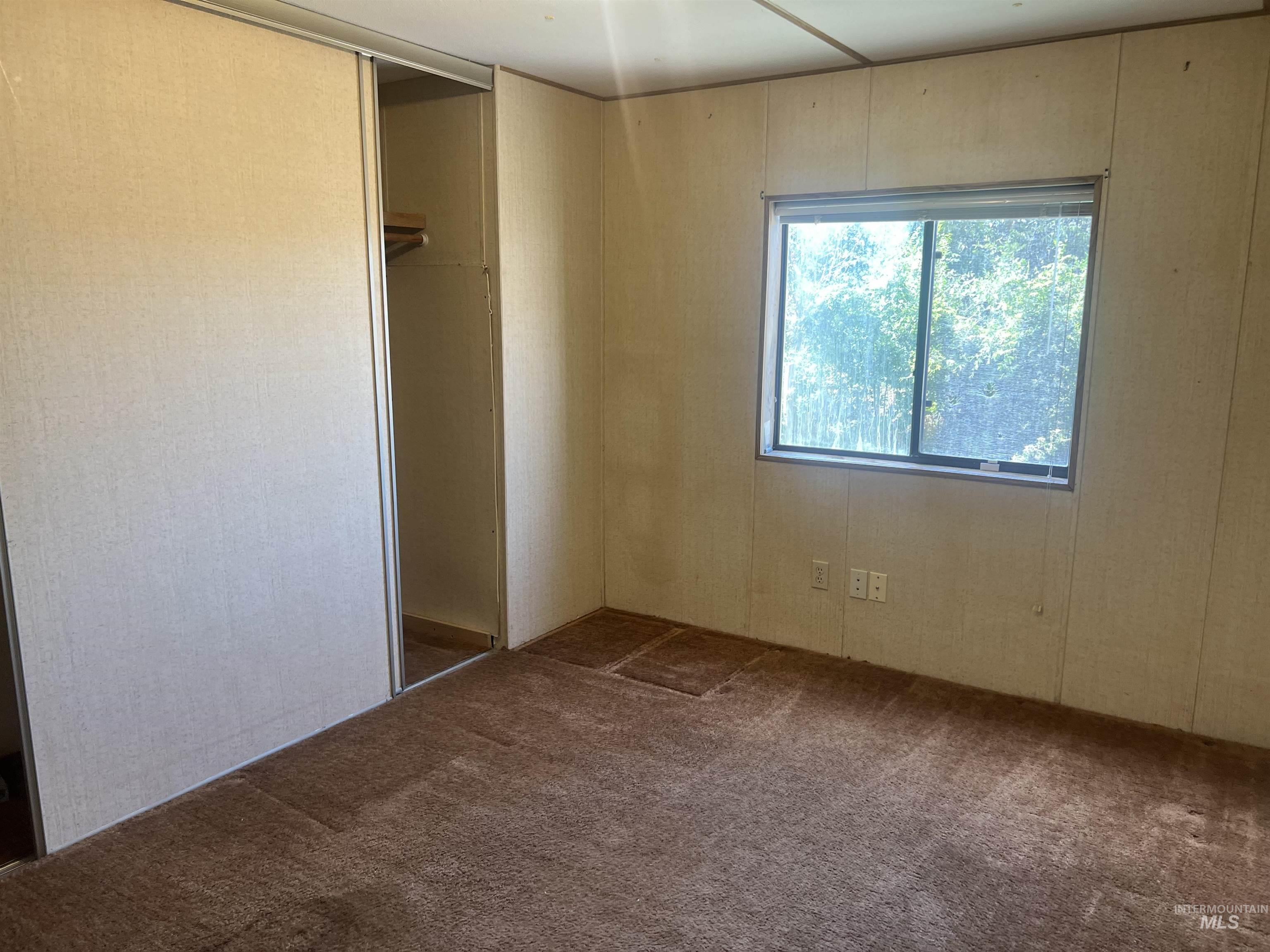 Unfurnished bedroom with dark colored carpet and a closet