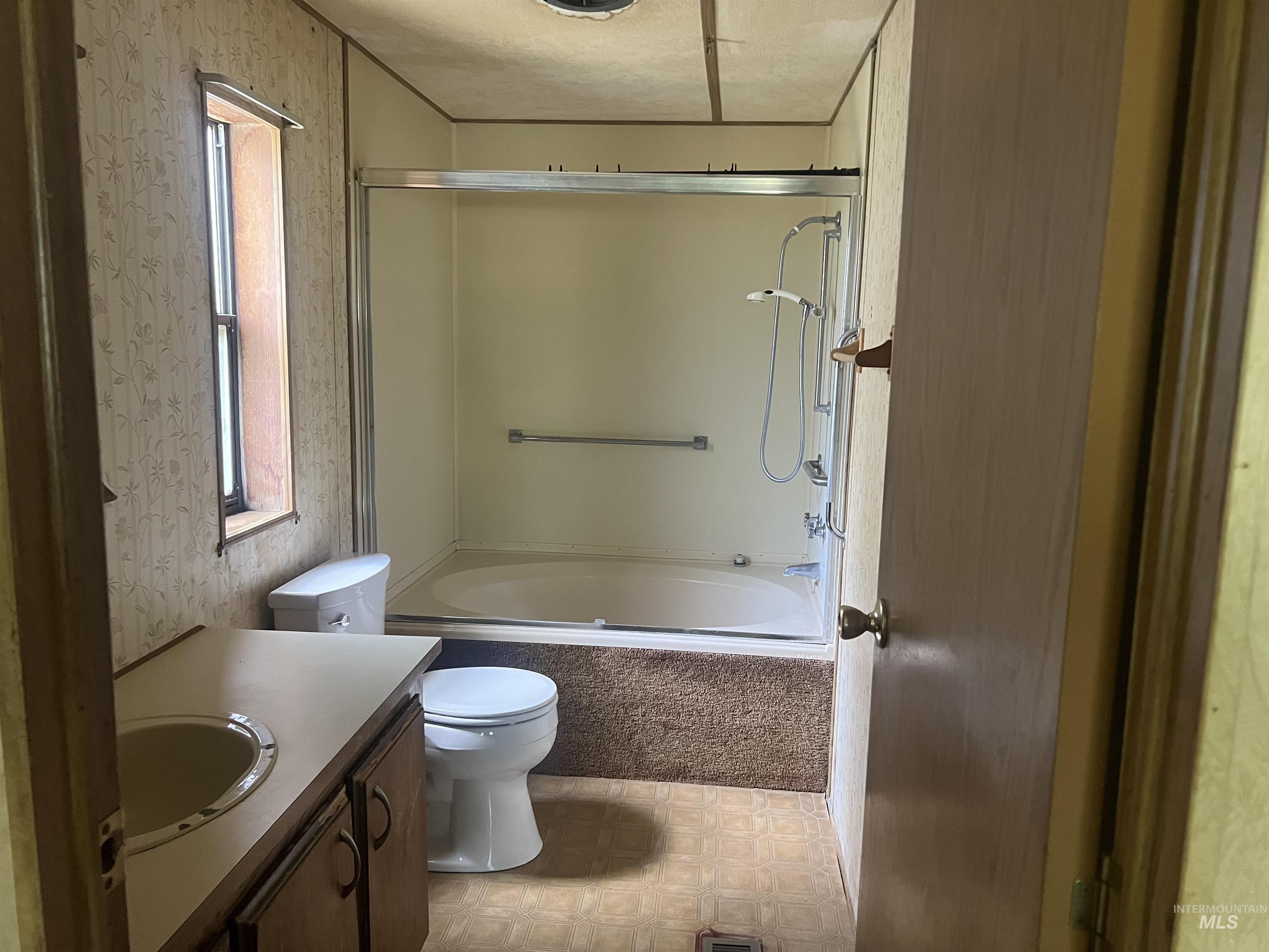 Full bathroom with shower / bath combination, vanity, and wallpapered walls