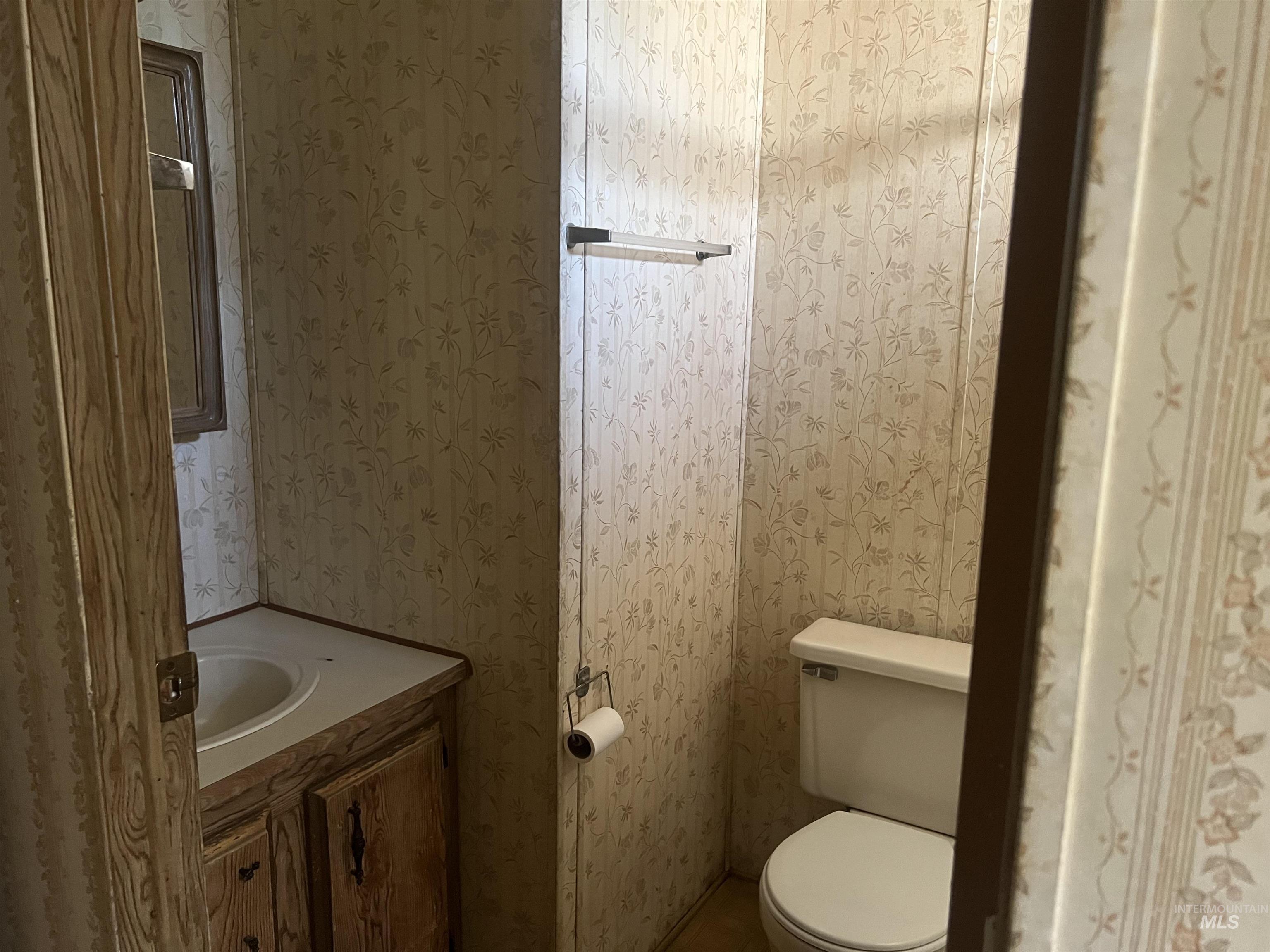 Bathroom with wallpapered walls and vanity