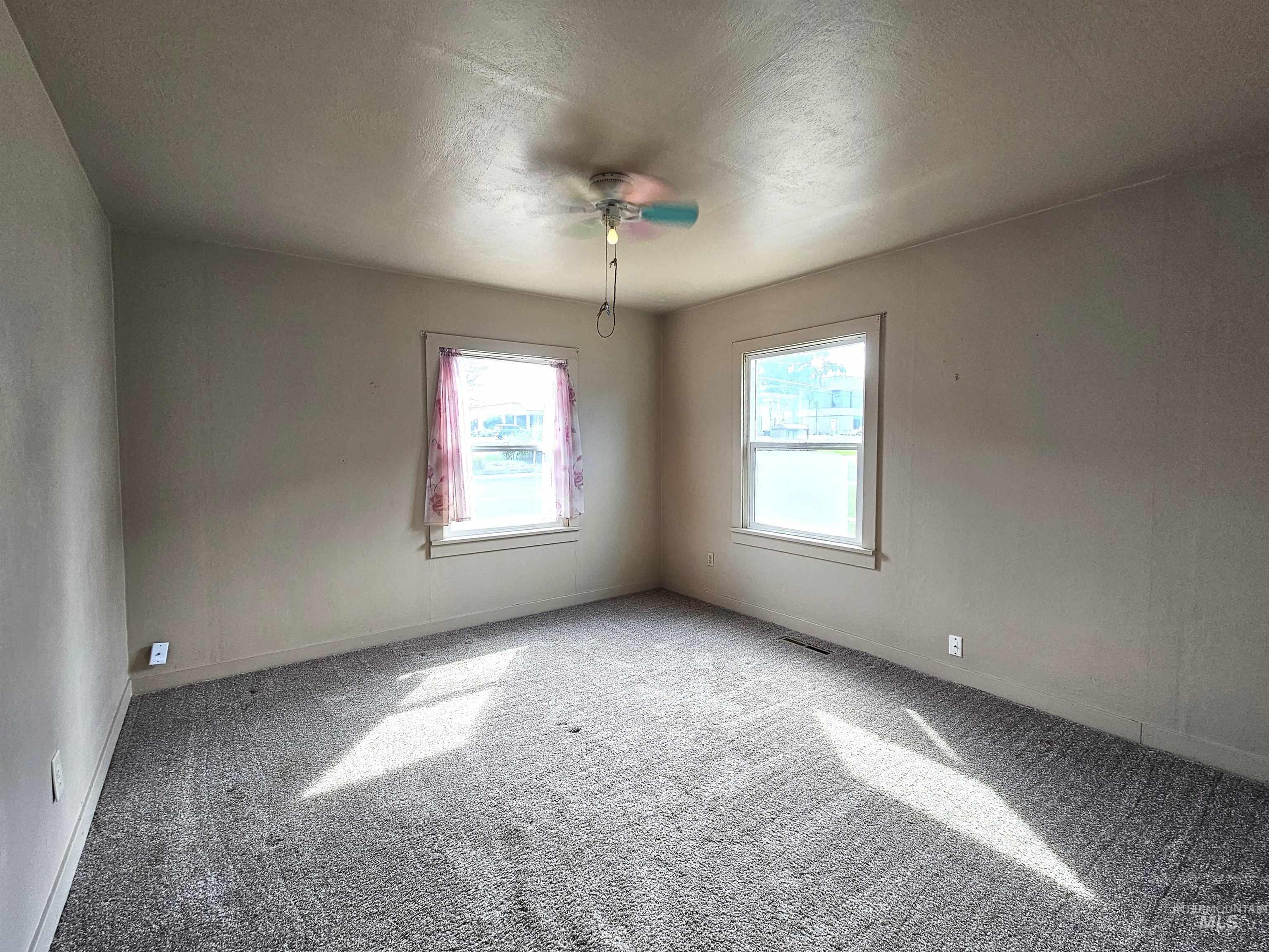 Carpeted empty room with plenty of natural light, a textured ceiling, and a ceiling fan