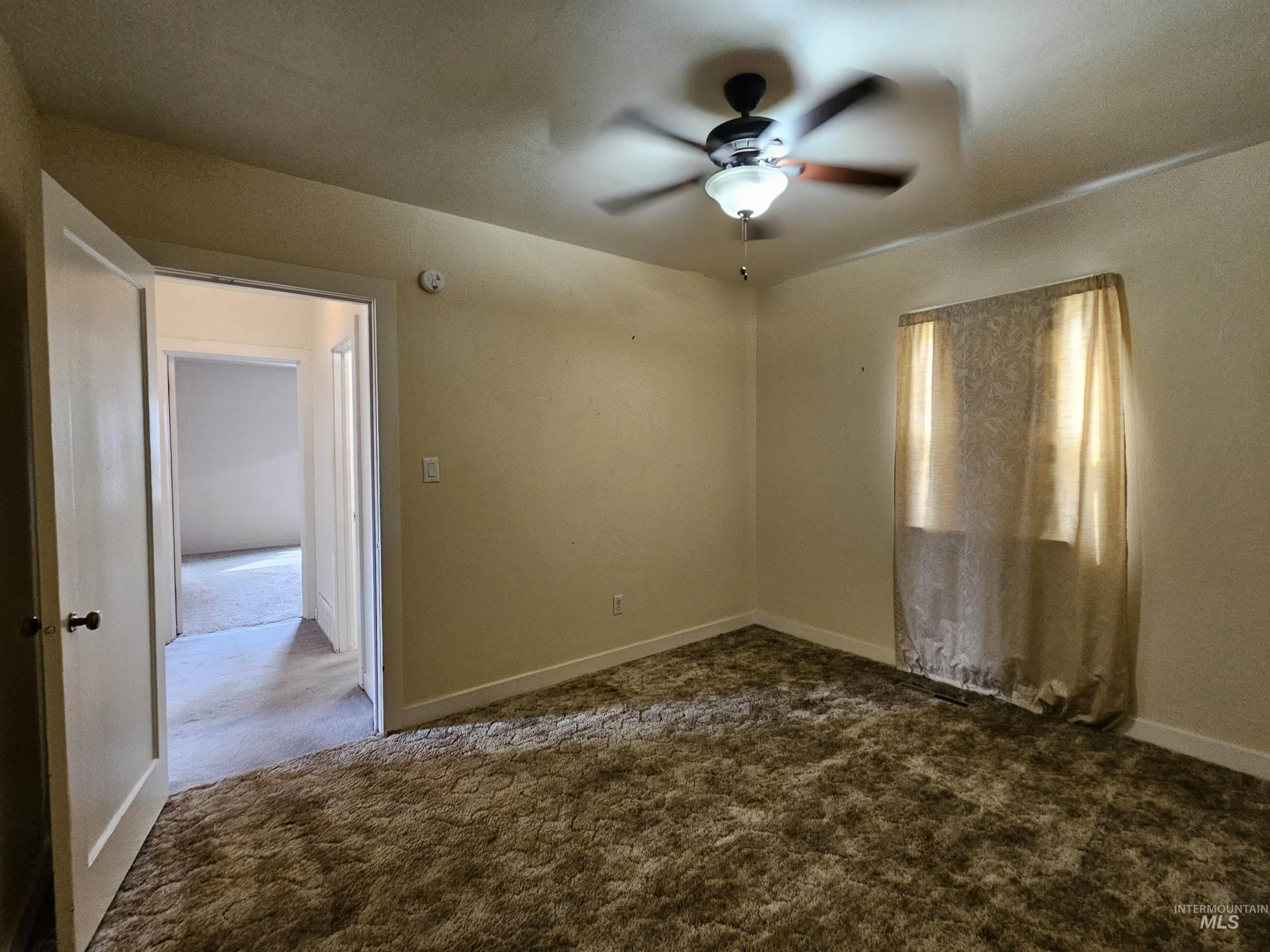 Empty room featuring dark carpet and ceiling fan