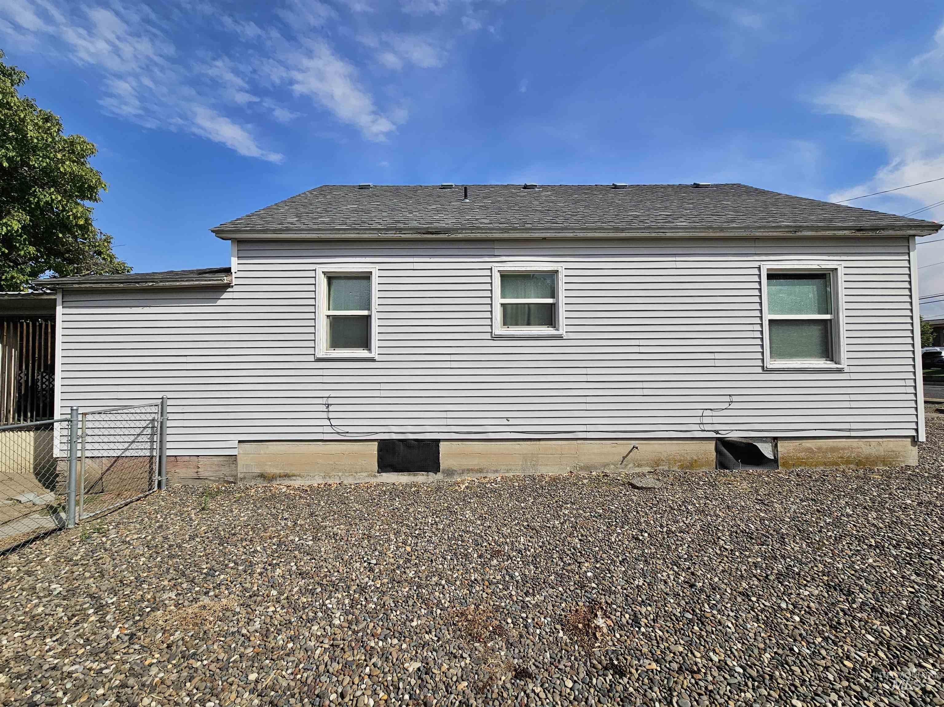 Rear view of property with a gate and roof with shingles