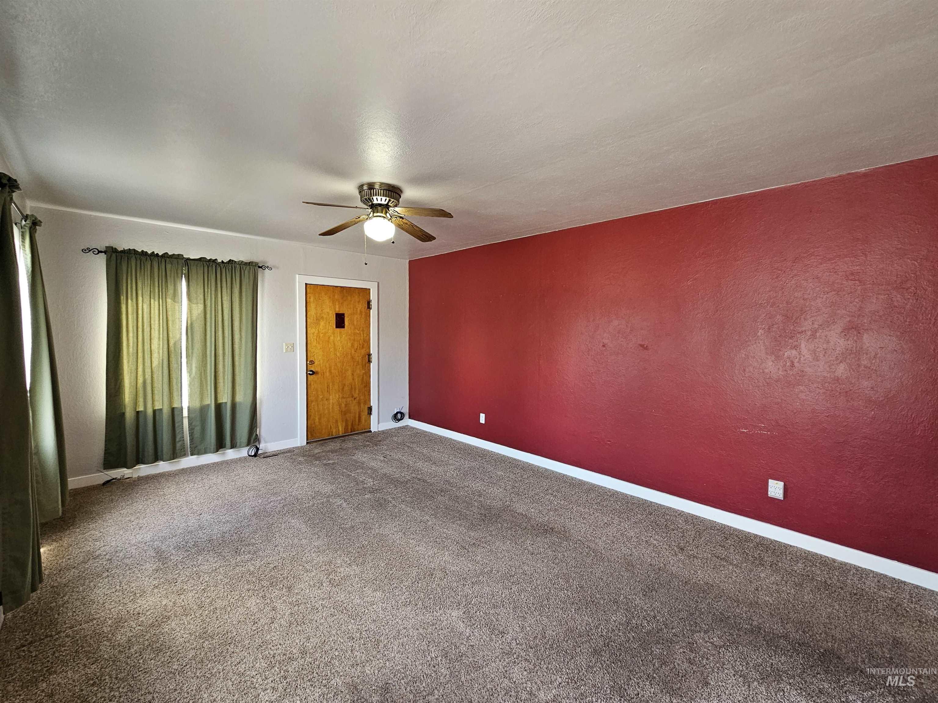 Spare room with carpet flooring, a ceiling fan, and a textured wall