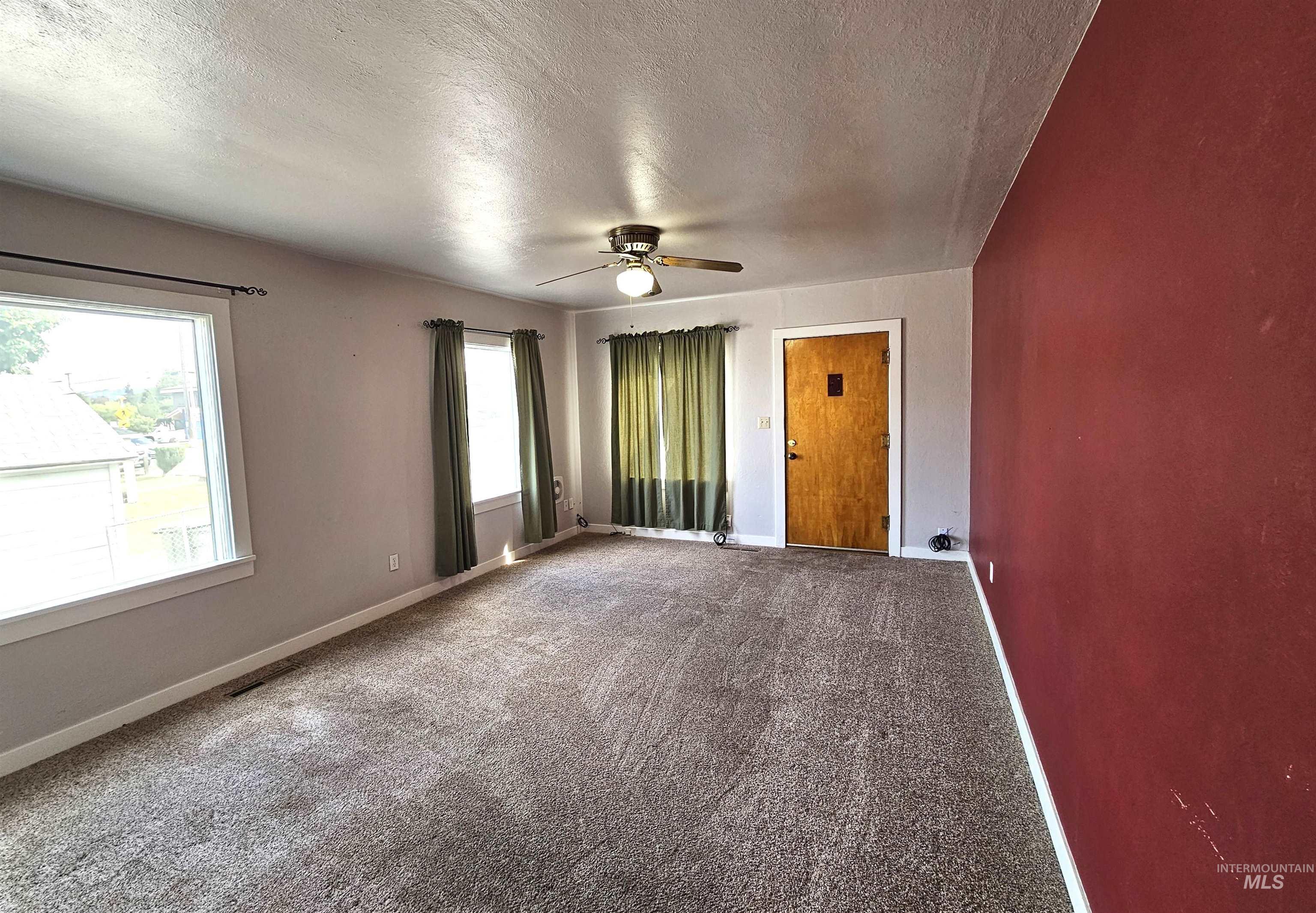 Carpeted empty room with a textured ceiling and ceiling fan