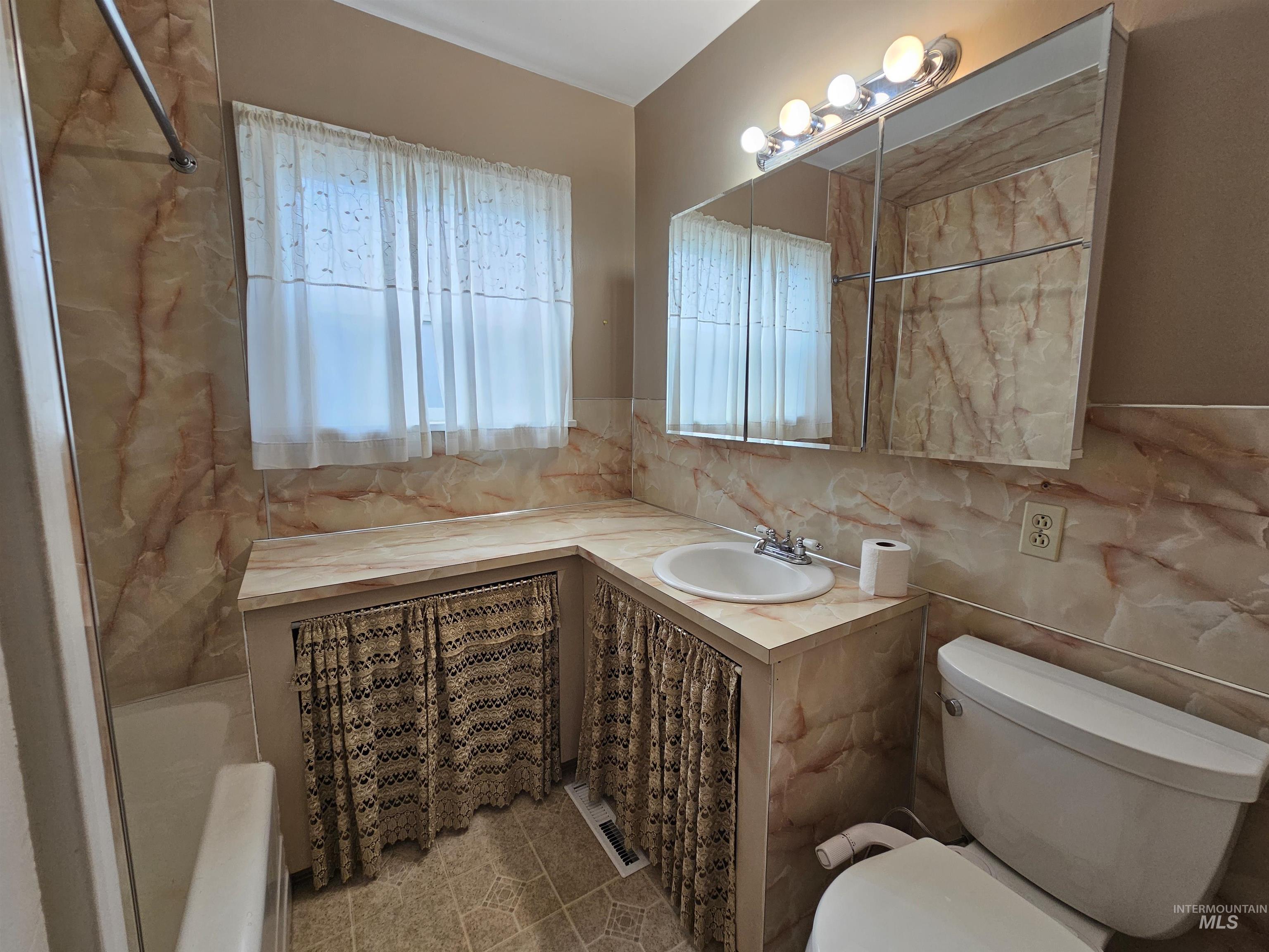 Bathroom featuring tile walls, vanity, and light tile patterned flooring