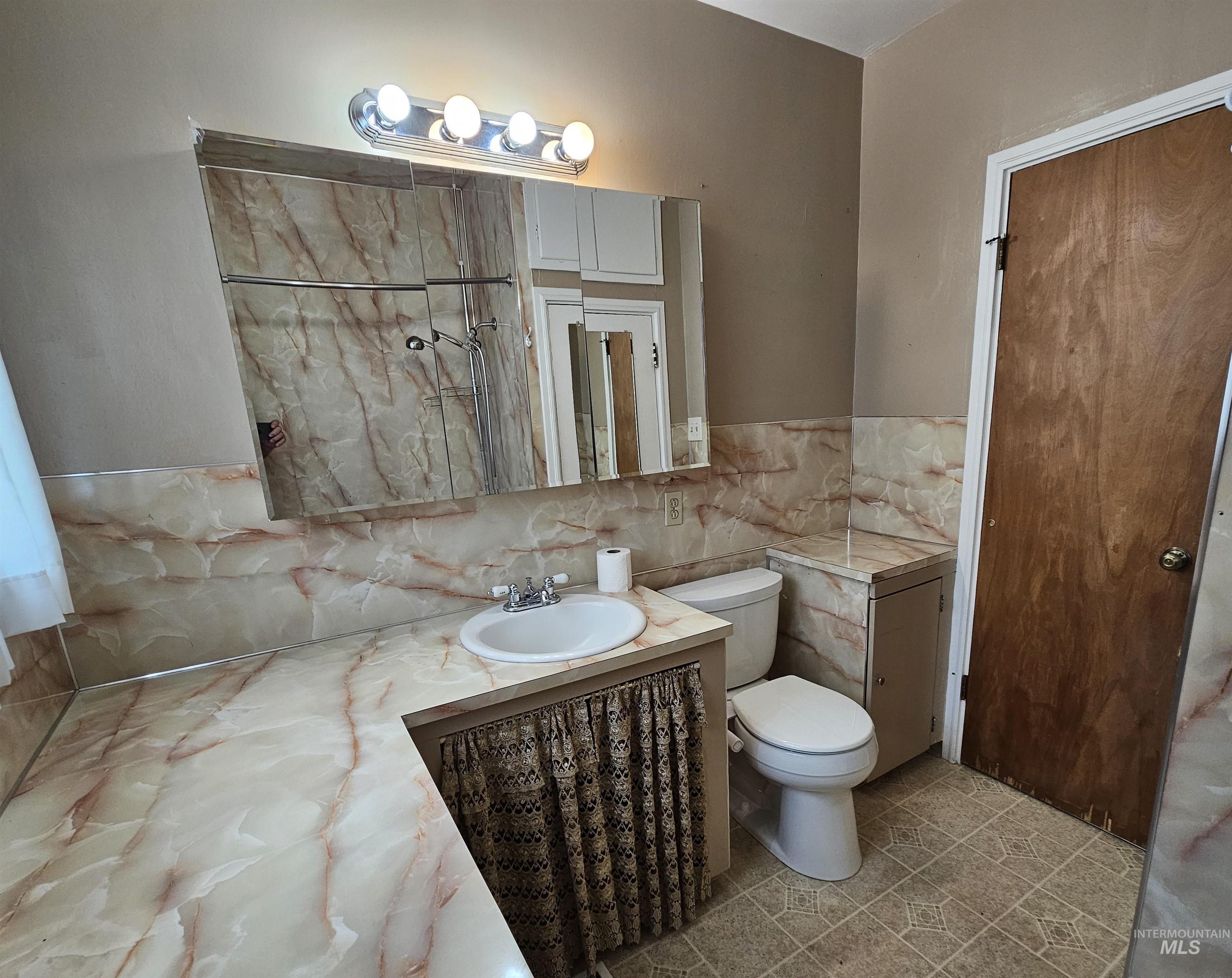 Bathroom featuring vanity, tile walls, a shower with door, and light tile patterned floors