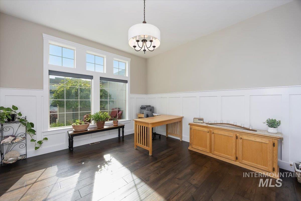 Office with a decorative wall, a wainscoted wall, dark wood-type flooring, and a chandelier
