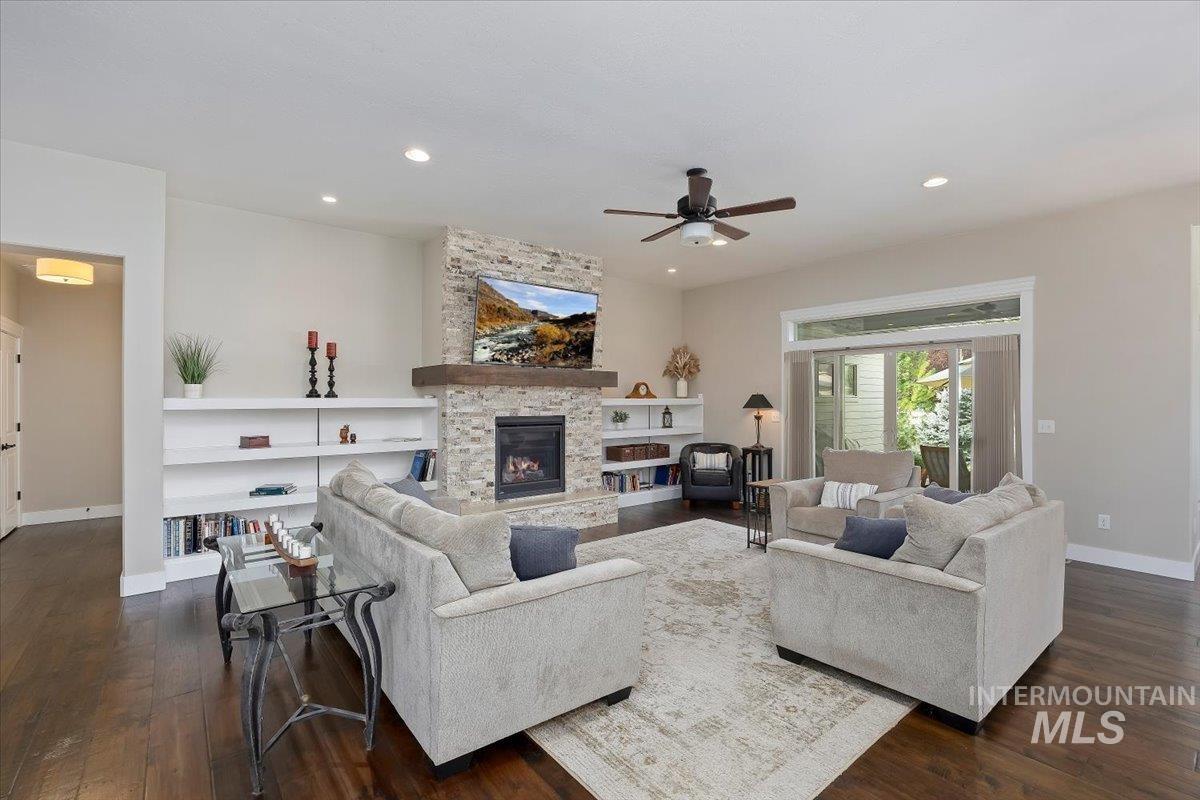 Living room featuring dark wood-type flooring, a fireplace, recessed lighting, and ceiling fan