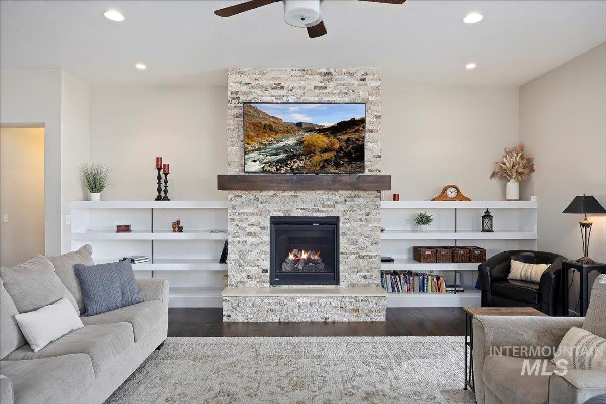 Living room featuring wood finished floors, recessed lighting, a stone fireplace, and ceiling fan