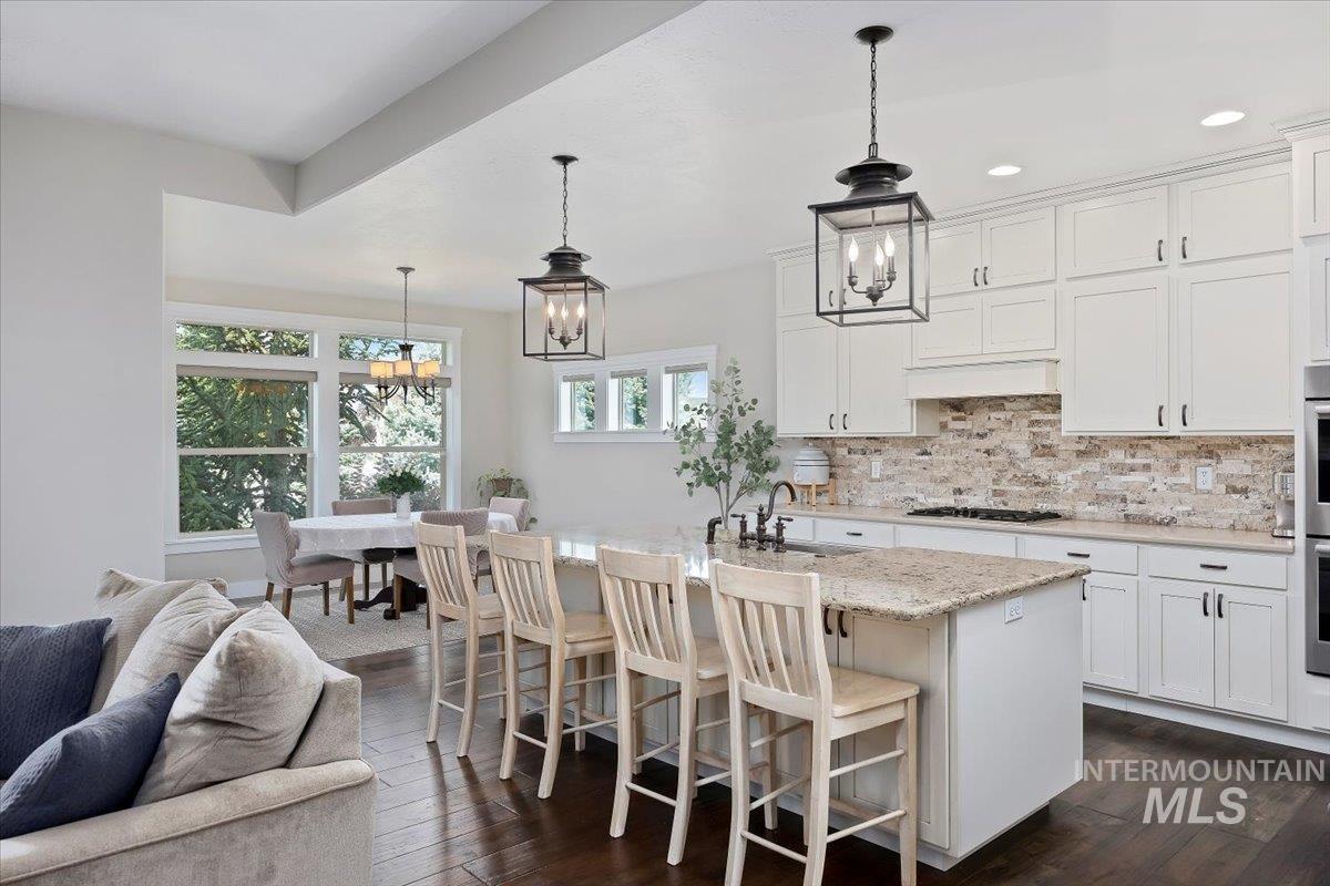 Kitchen with tasteful backsplash, a chandelier, a breakfast bar area, decorative light fixtures, and recessed lighting