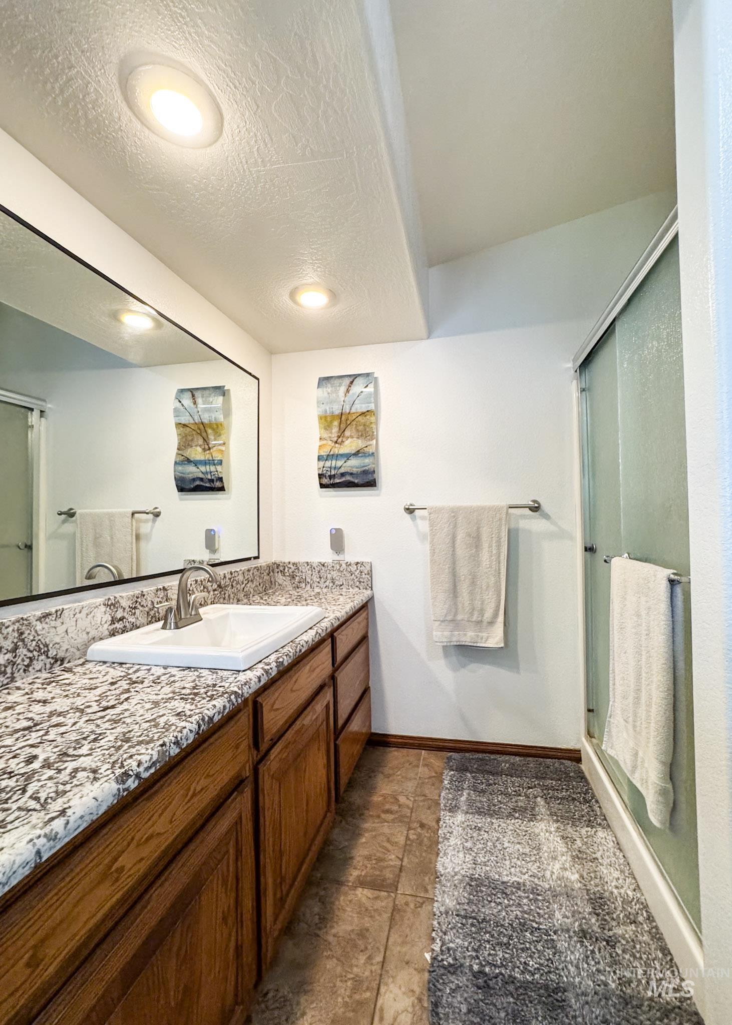 Bathroom featuring vanity, a textured ceiling, and a shower stall