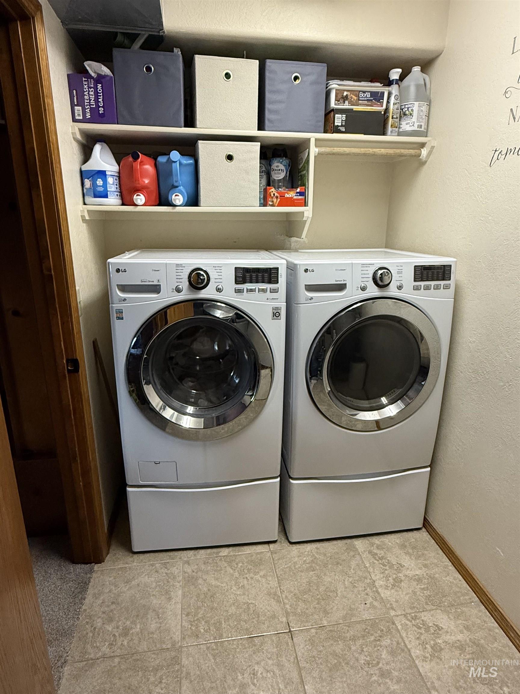 Laundry room featuring a textured wall, independent washer and dryer, and light tile patterned floors