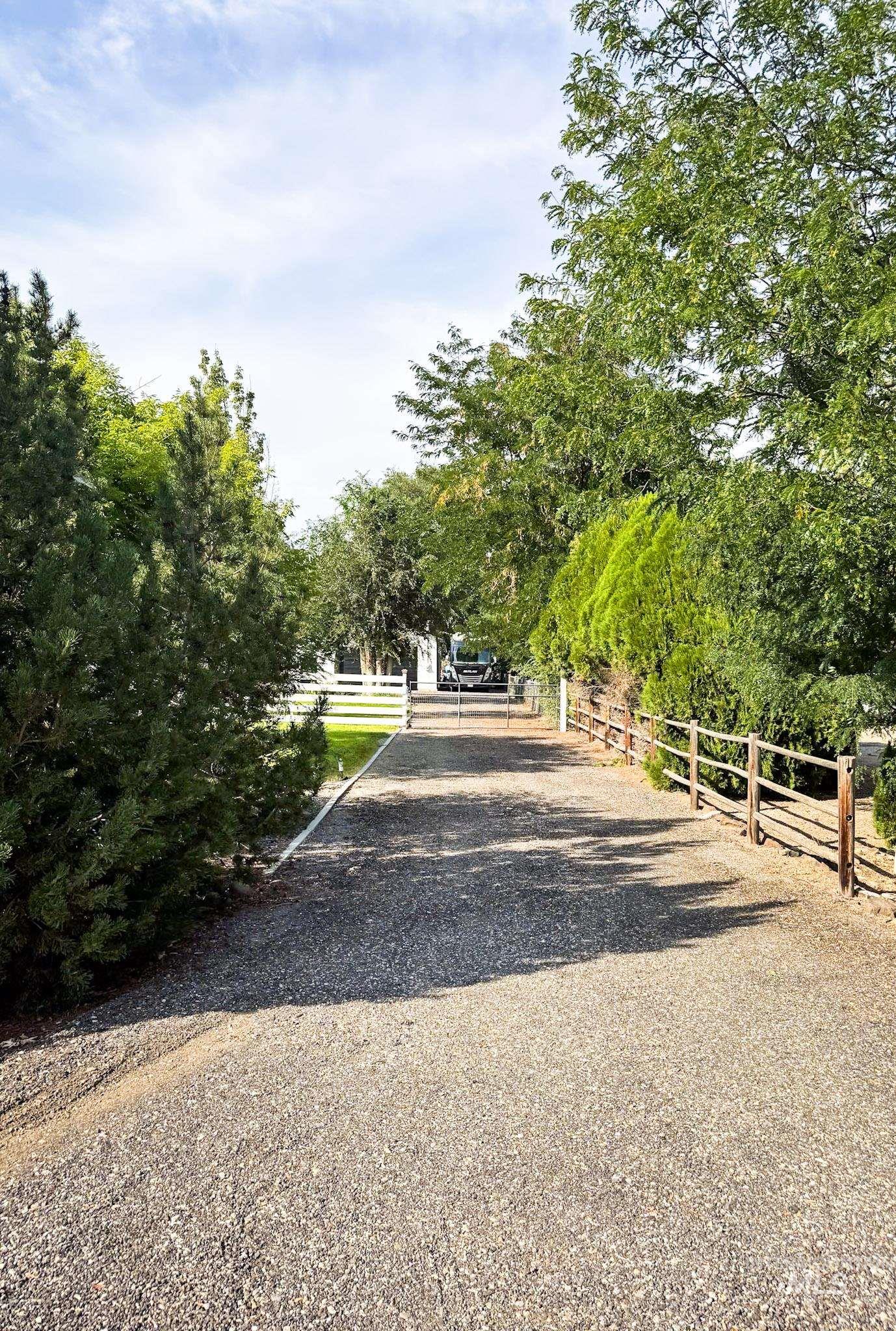 View of dirt / gravel driveway featuring a gated entry