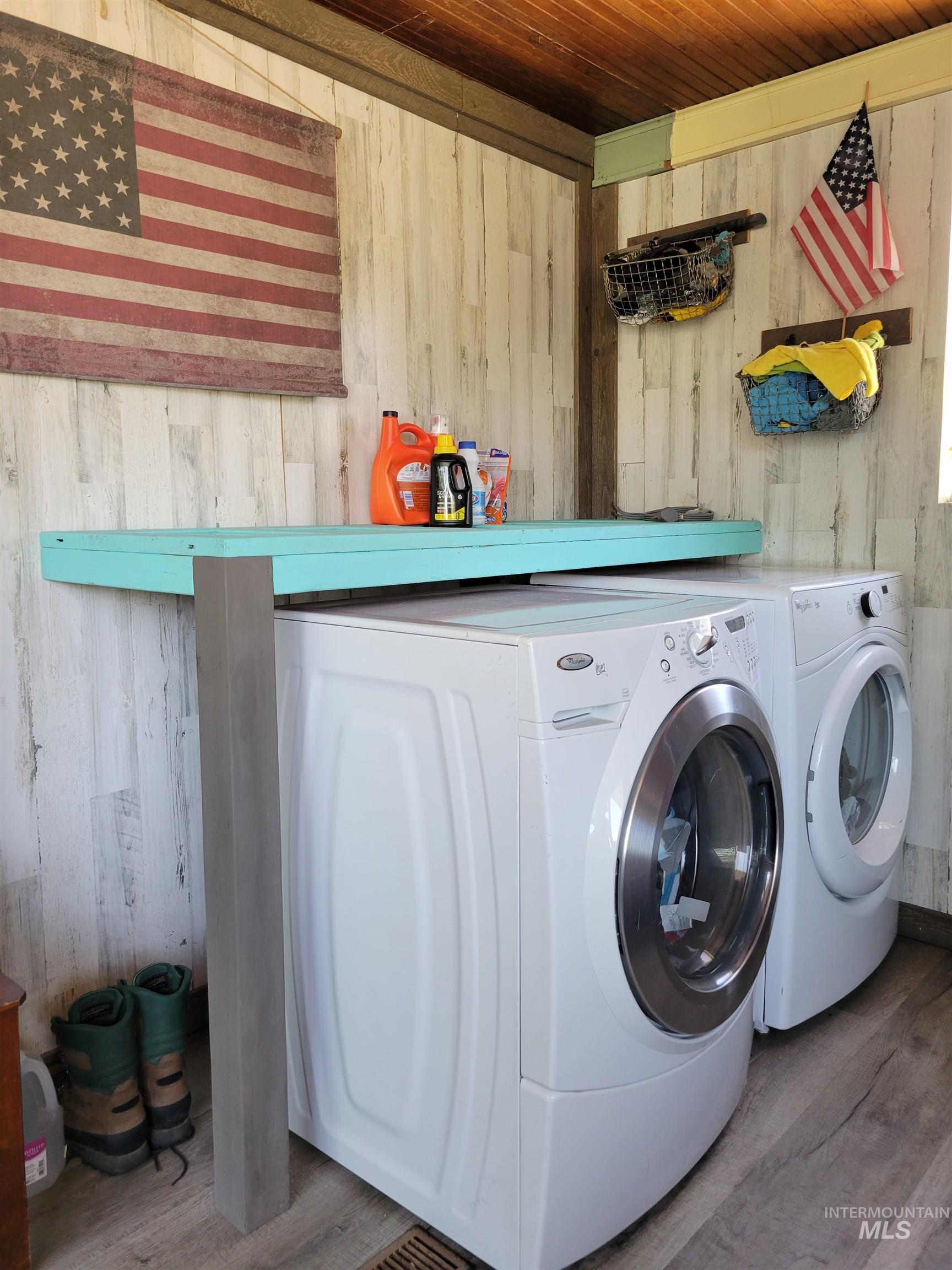 Laundry area with wooden walls, wood finished floors, wood ceiling, and washing machine and clothes dryer