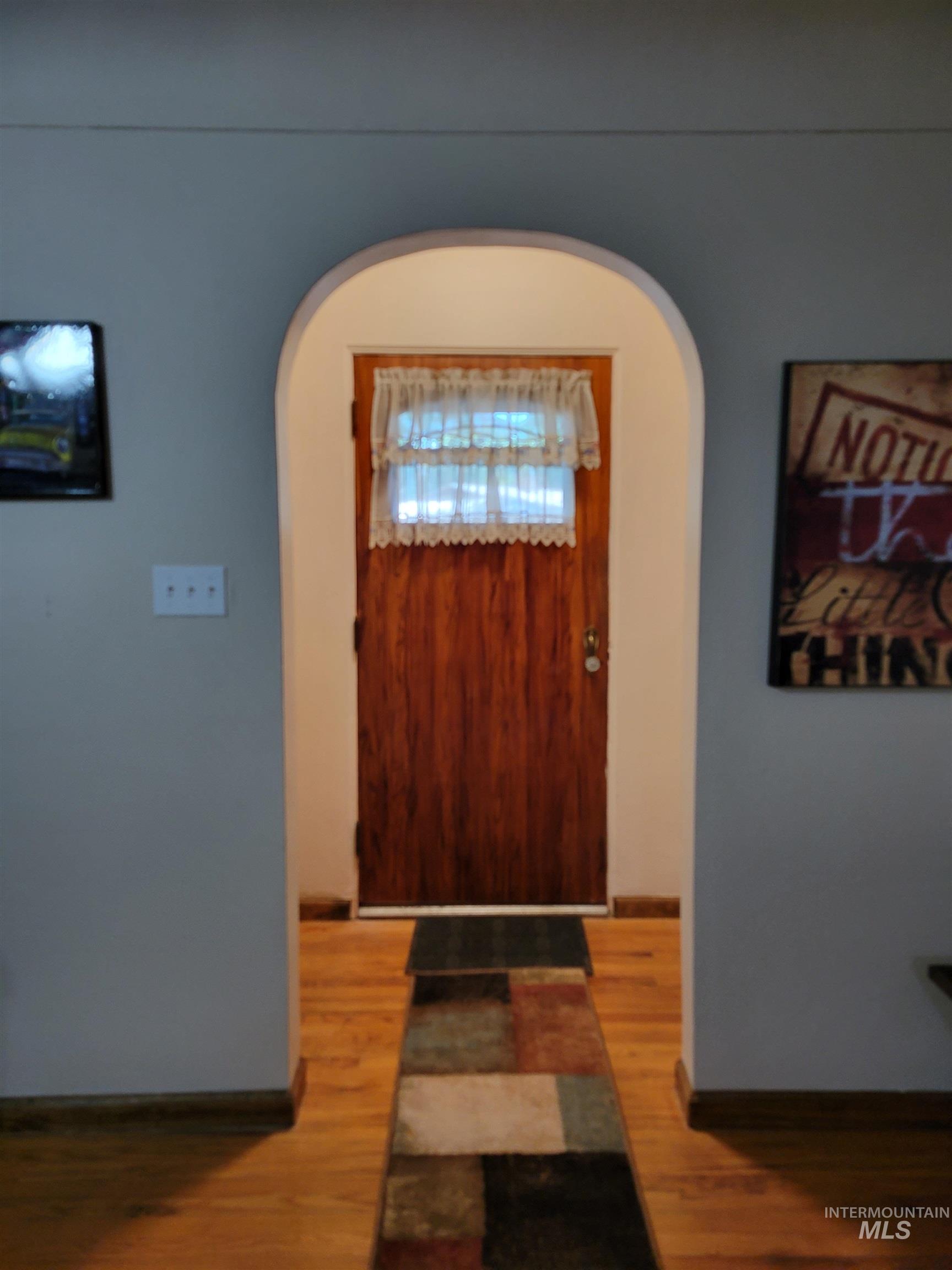 Entryway with arched walkways and wood finished floors