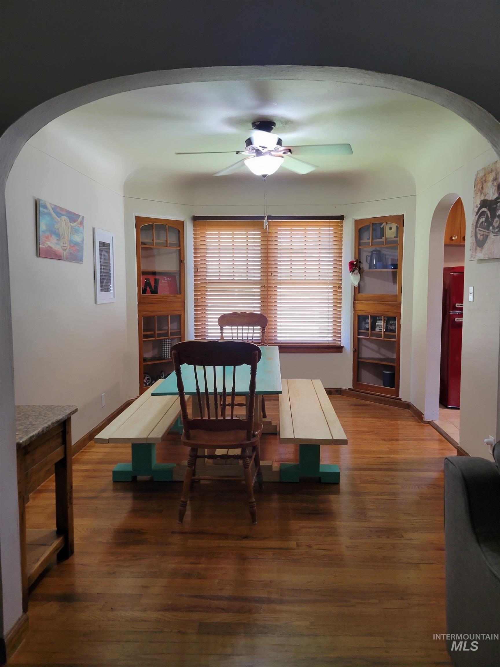 Dining space featuring arched walkways, wood finished floors, and a ceiling fan