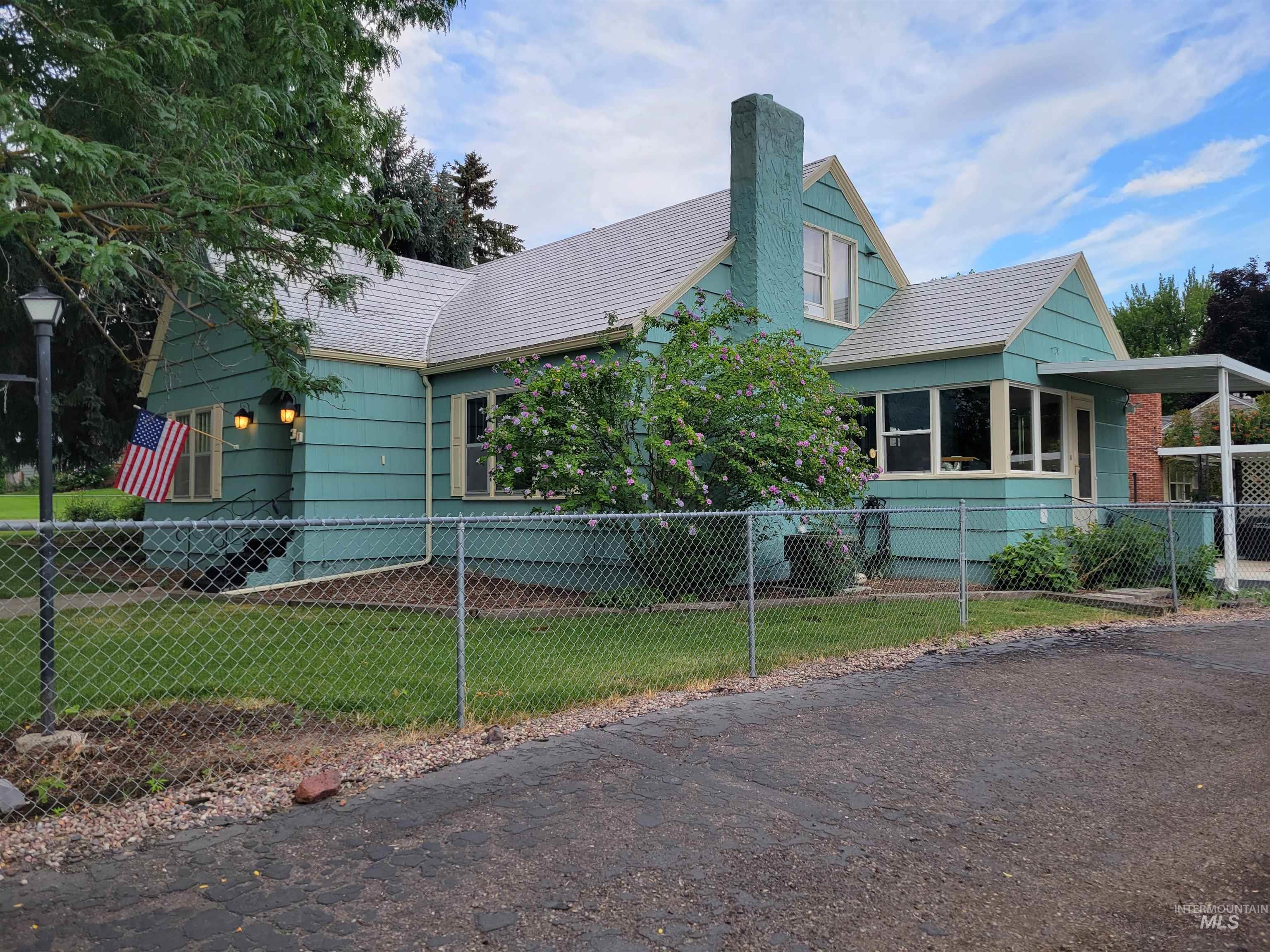 View of front of home featuring a chimney, a fenced front yard, and a sunroom