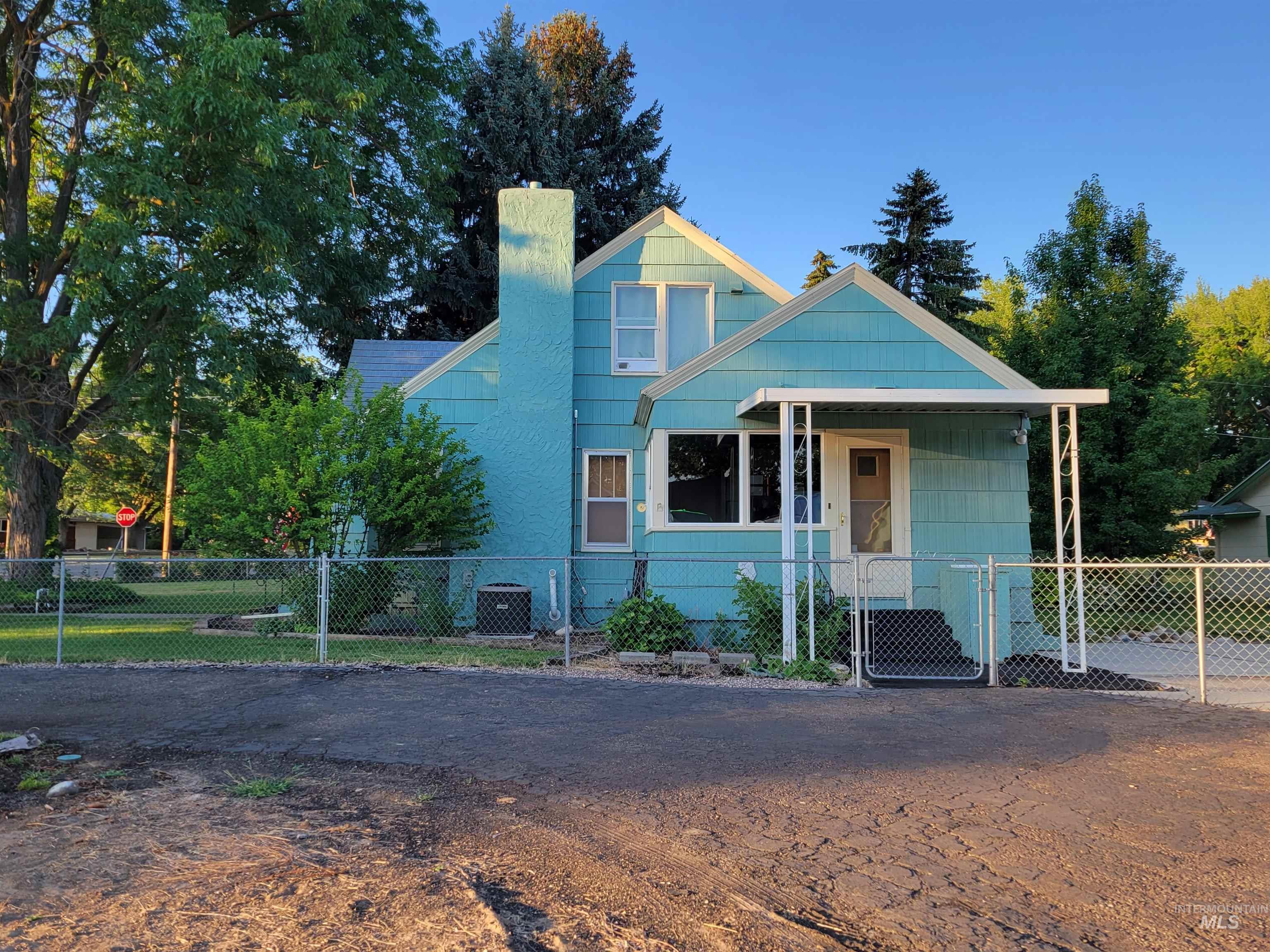 View of front facade featuring a chimney, a fenced front yard, a porch, and a gate