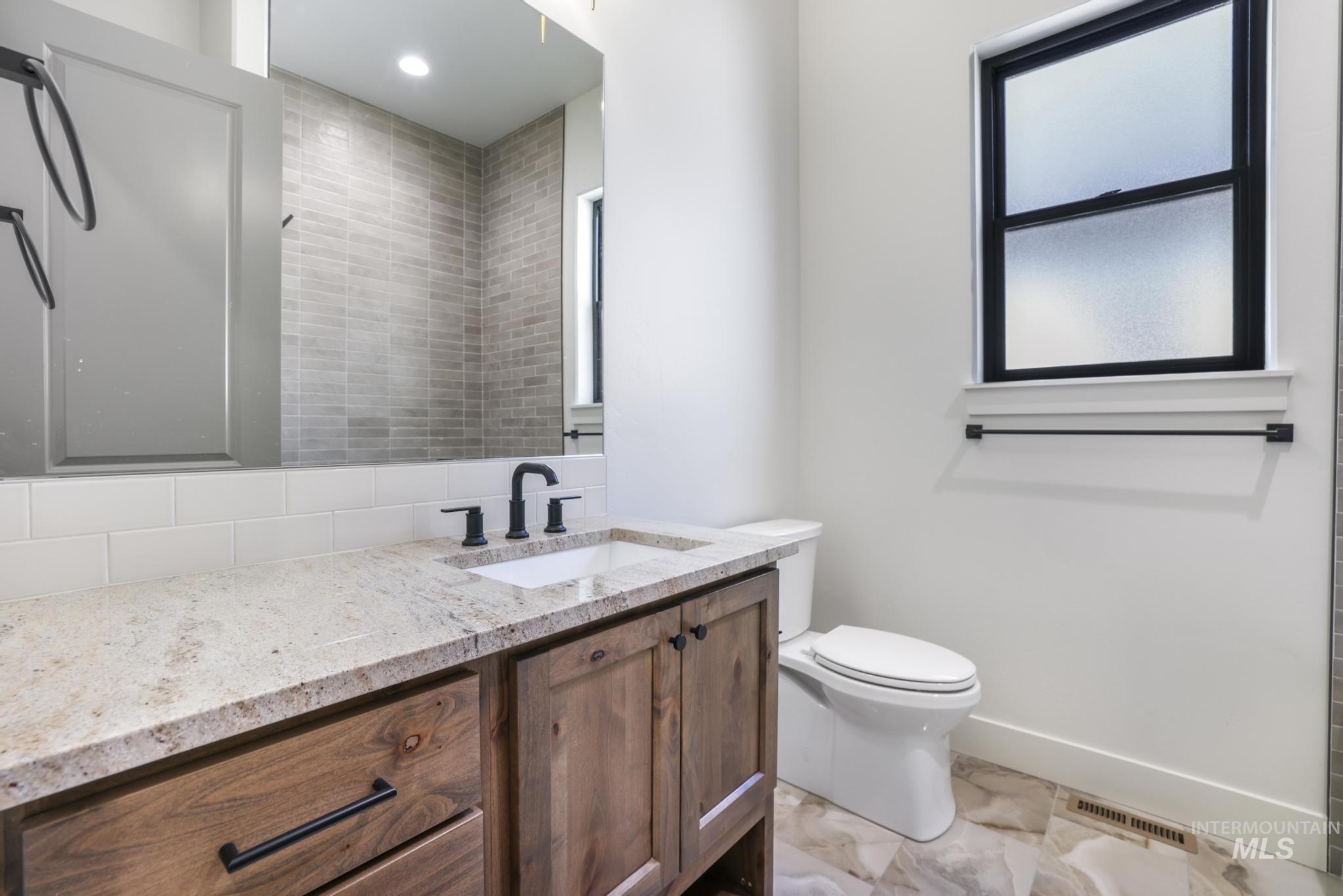 Bathroom with vanity and tasteful backsplash
