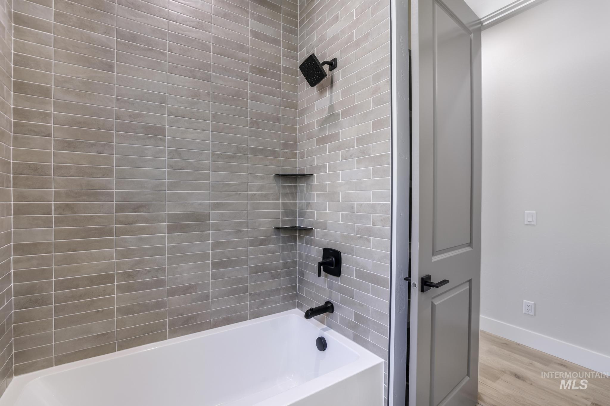 Bathroom with bathing tub / shower combination and wood finished floors