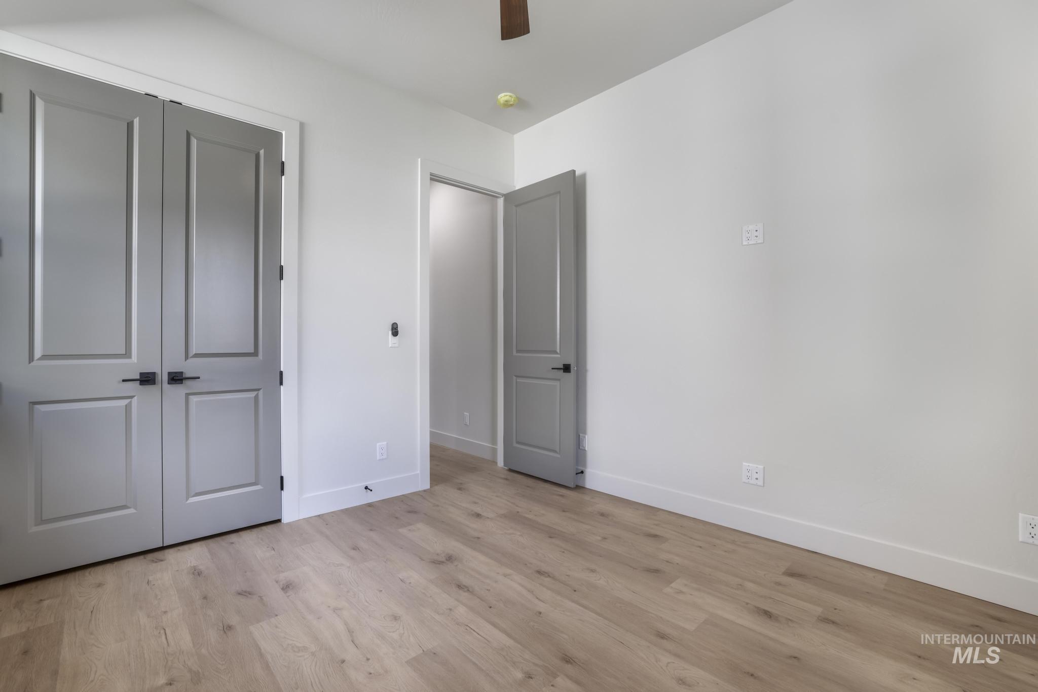 Unfurnished bedroom with light wood finished floors, a closet, and a ceiling fan