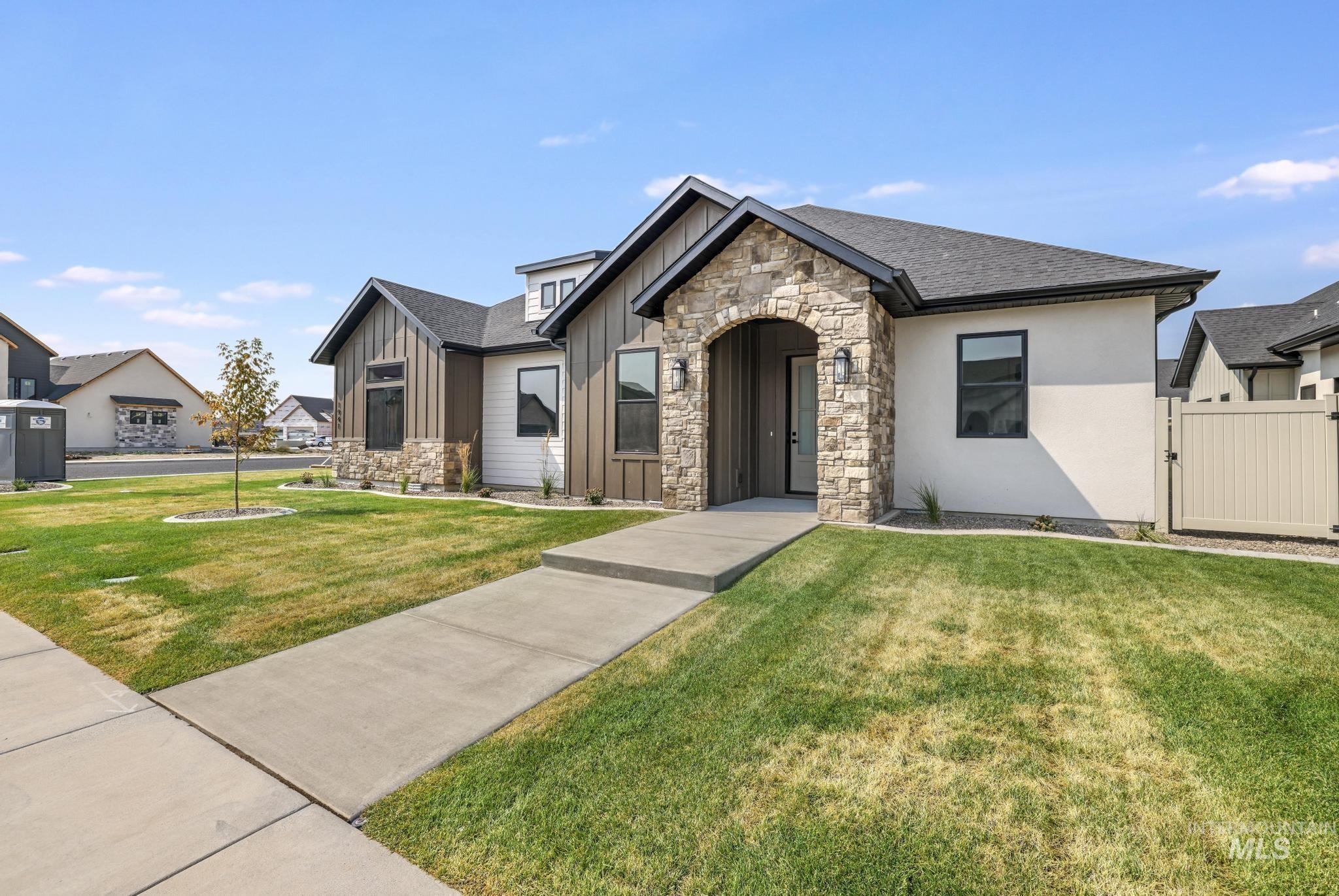 View of front of home featuring board and batten siding, stone siding, a front yard, and a residential view