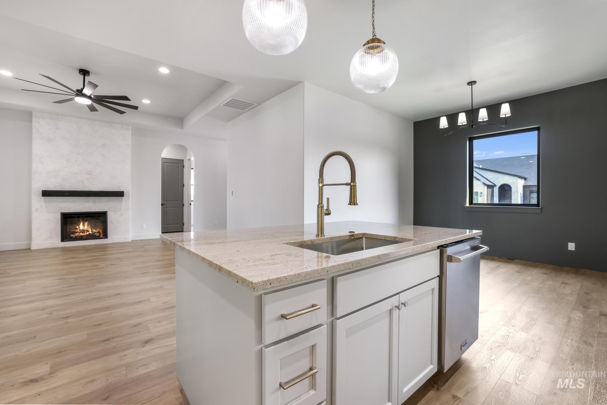 Kitchen featuring white cabinetry, light stone countertops, decorative light fixtures, light wood-style flooring, and recessed lighting