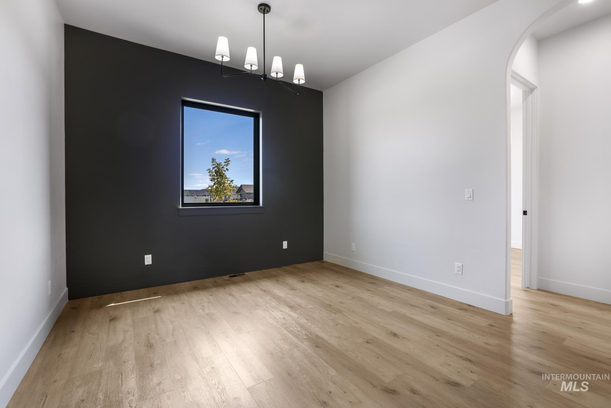 Unfurnished dining area featuring light wood-style floors and arched walkways