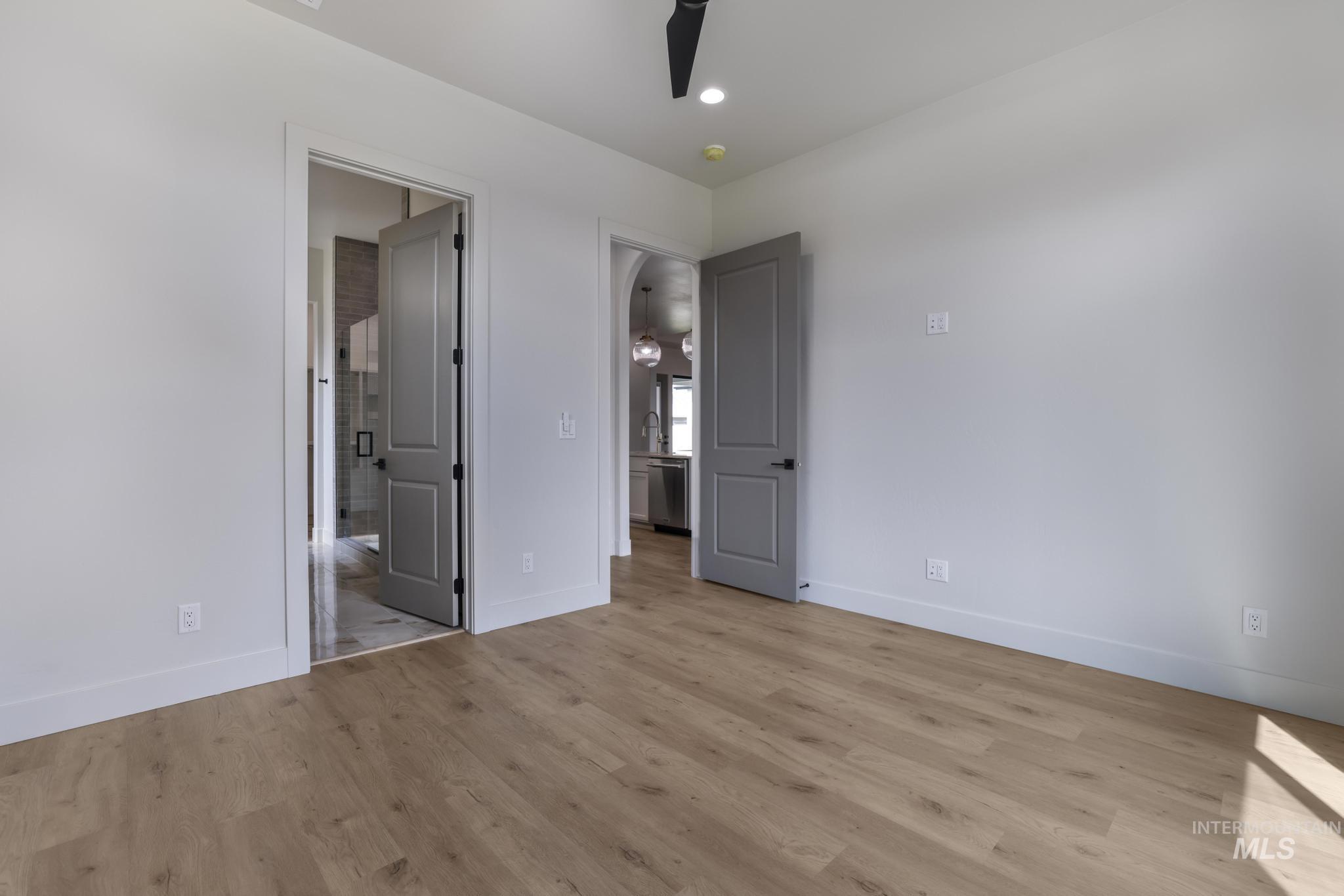 Unfurnished bedroom featuring light wood-type flooring, a ceiling fan, connected bathroom, and recessed lighting